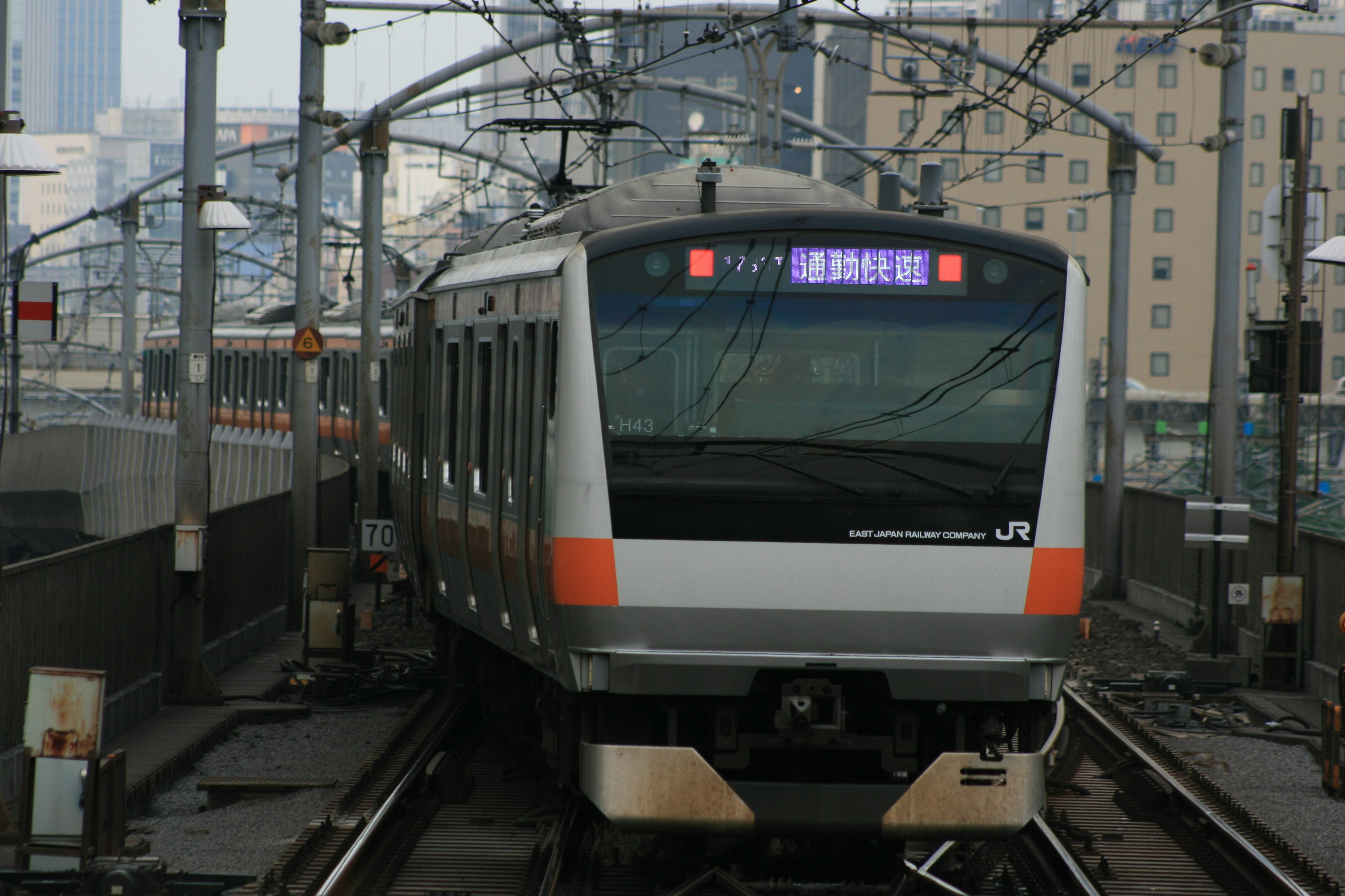 新幹線の駅に停車中の列車 鉄道の線路と都市の風景が背景