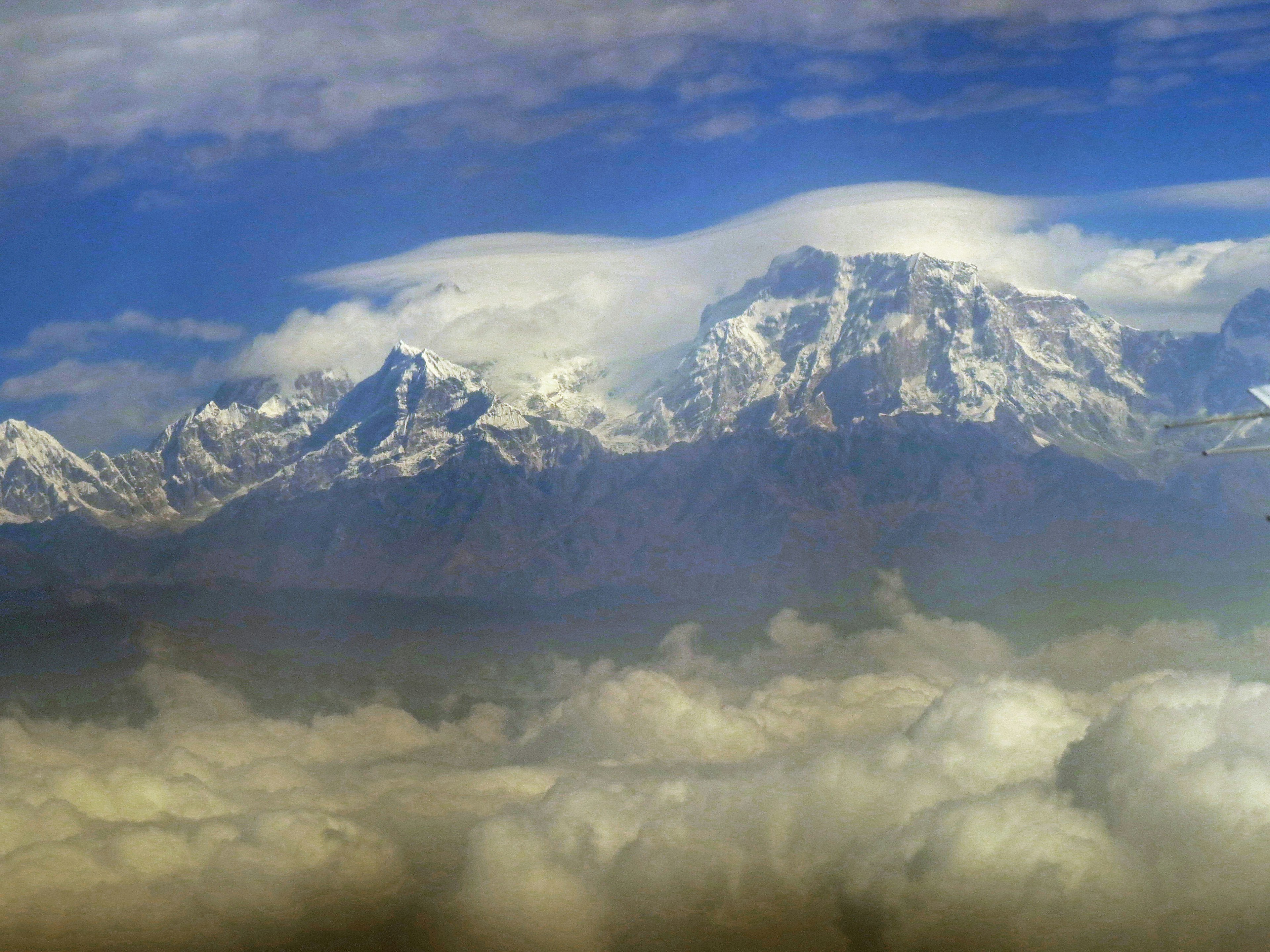 Snow-capped mountains towering above a sea of clouds