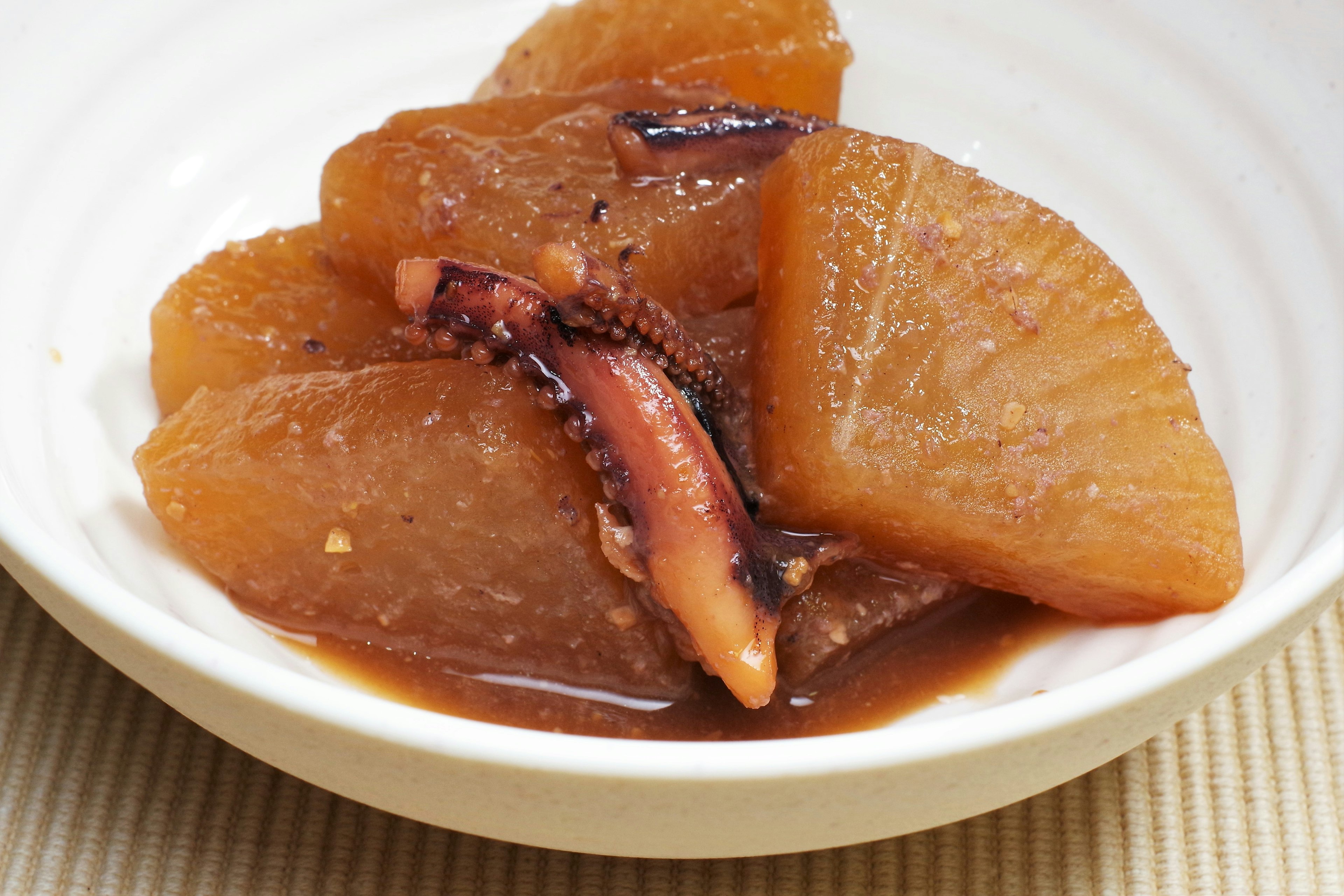 Daikon guisado dulce y salado con calamar servido en un tazón blanco