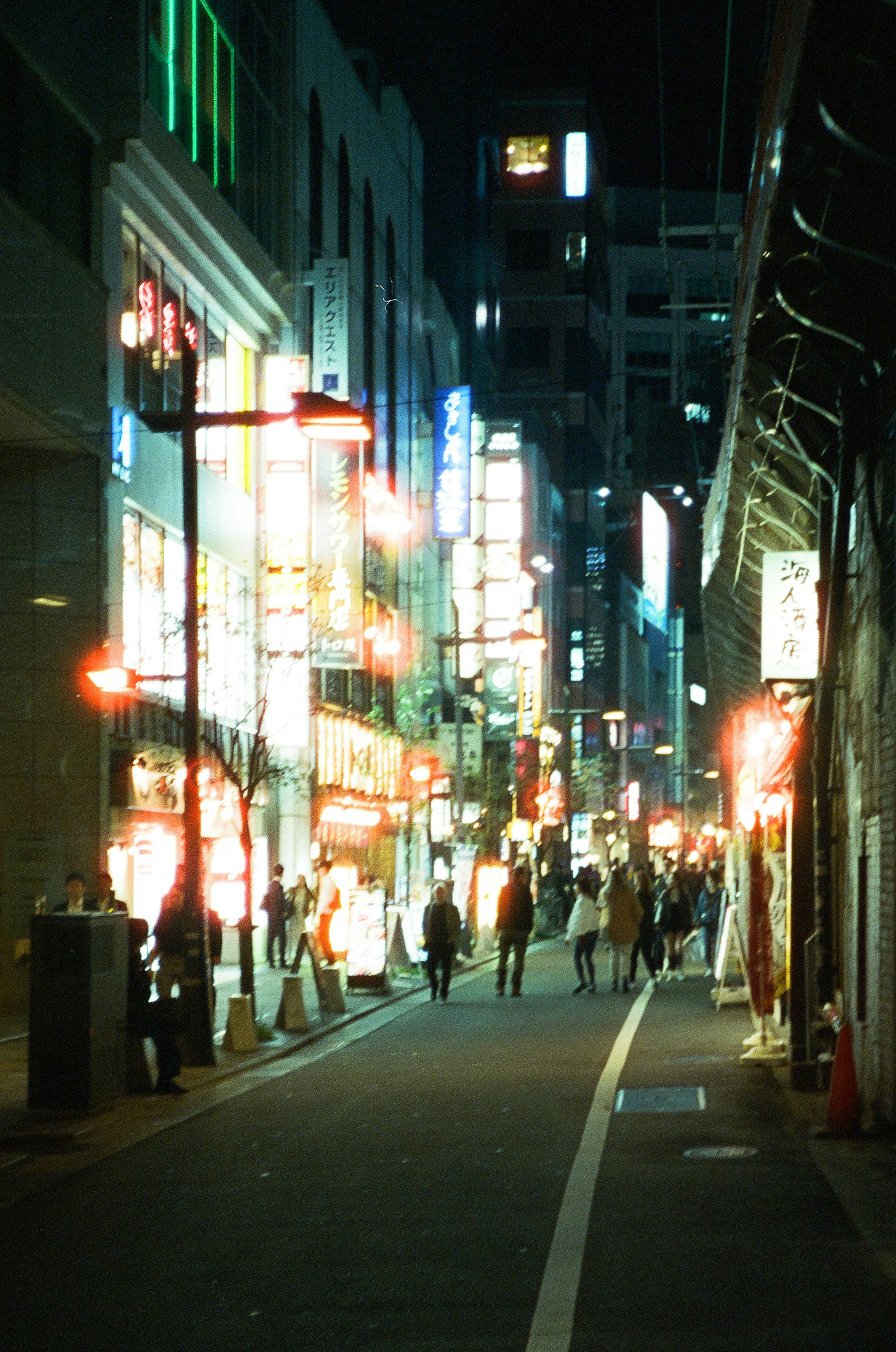 People walking in a vibrant neon-lit street at night