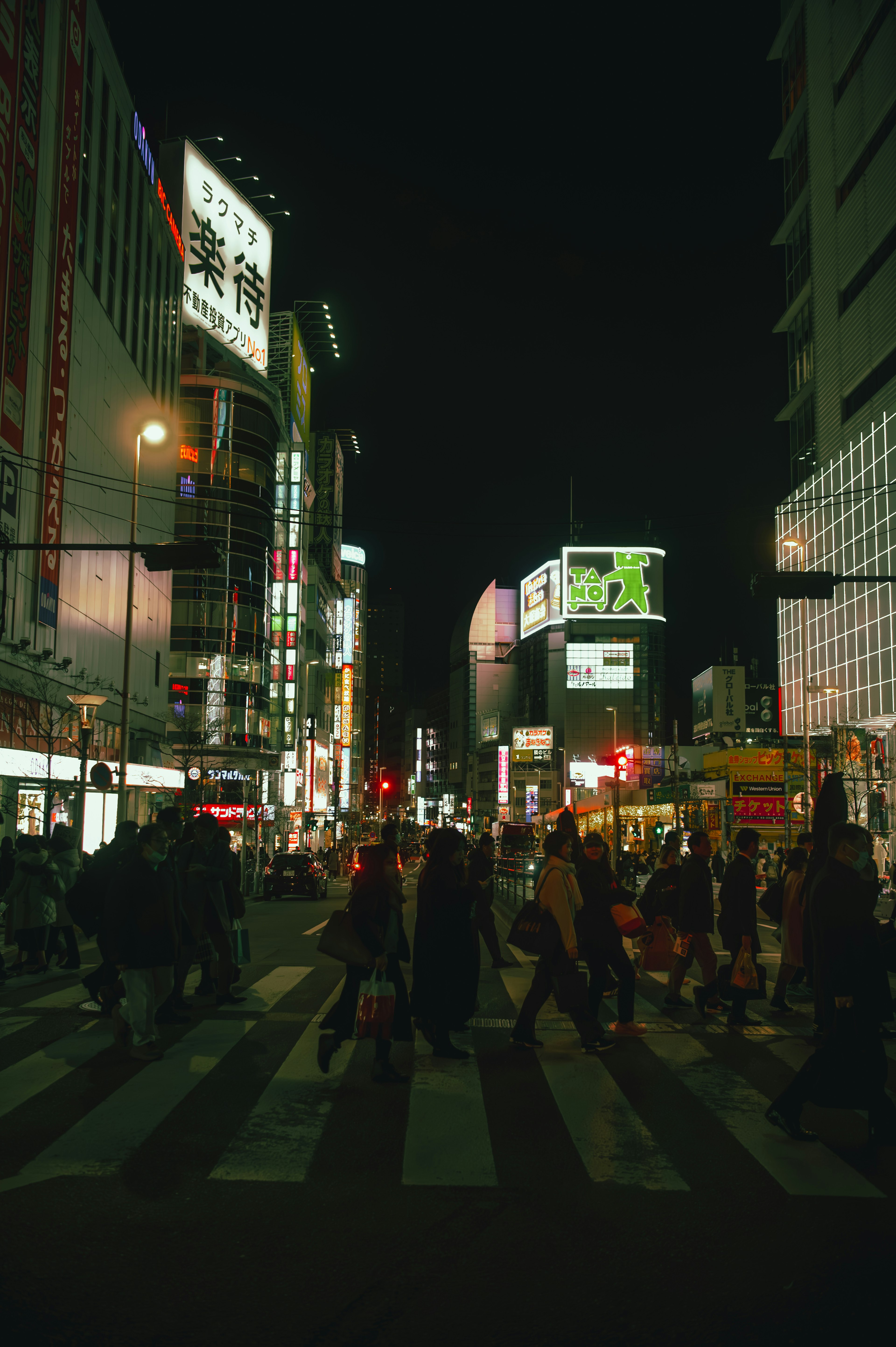 夜の街並みを歩く人々とネオンの看板