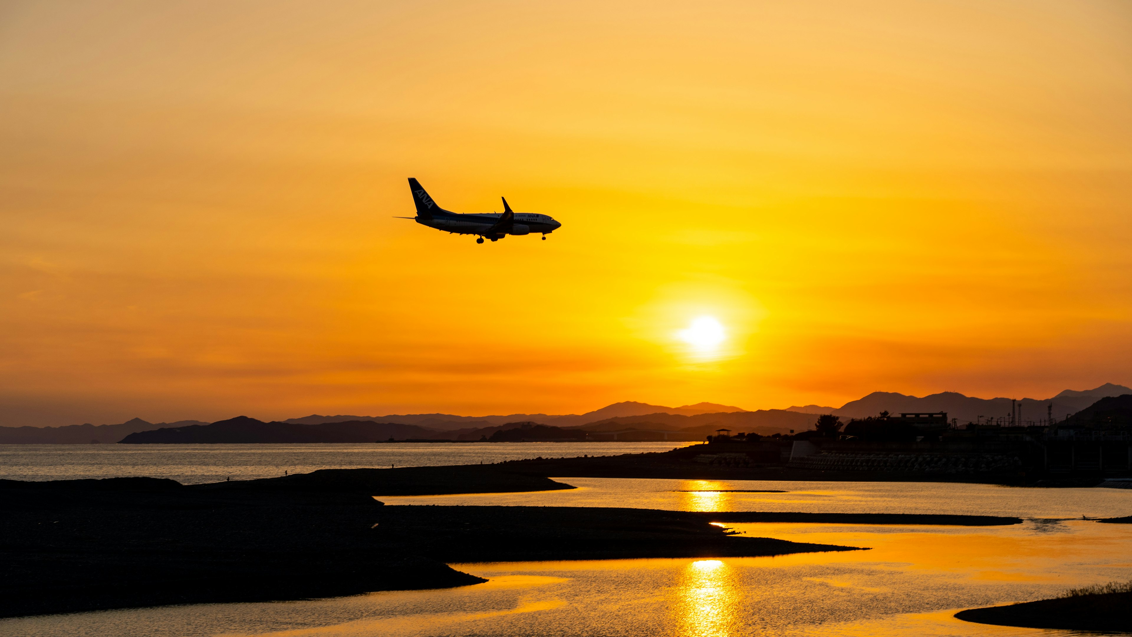 夕日を背景に飛行機が飛んでいる海の風景