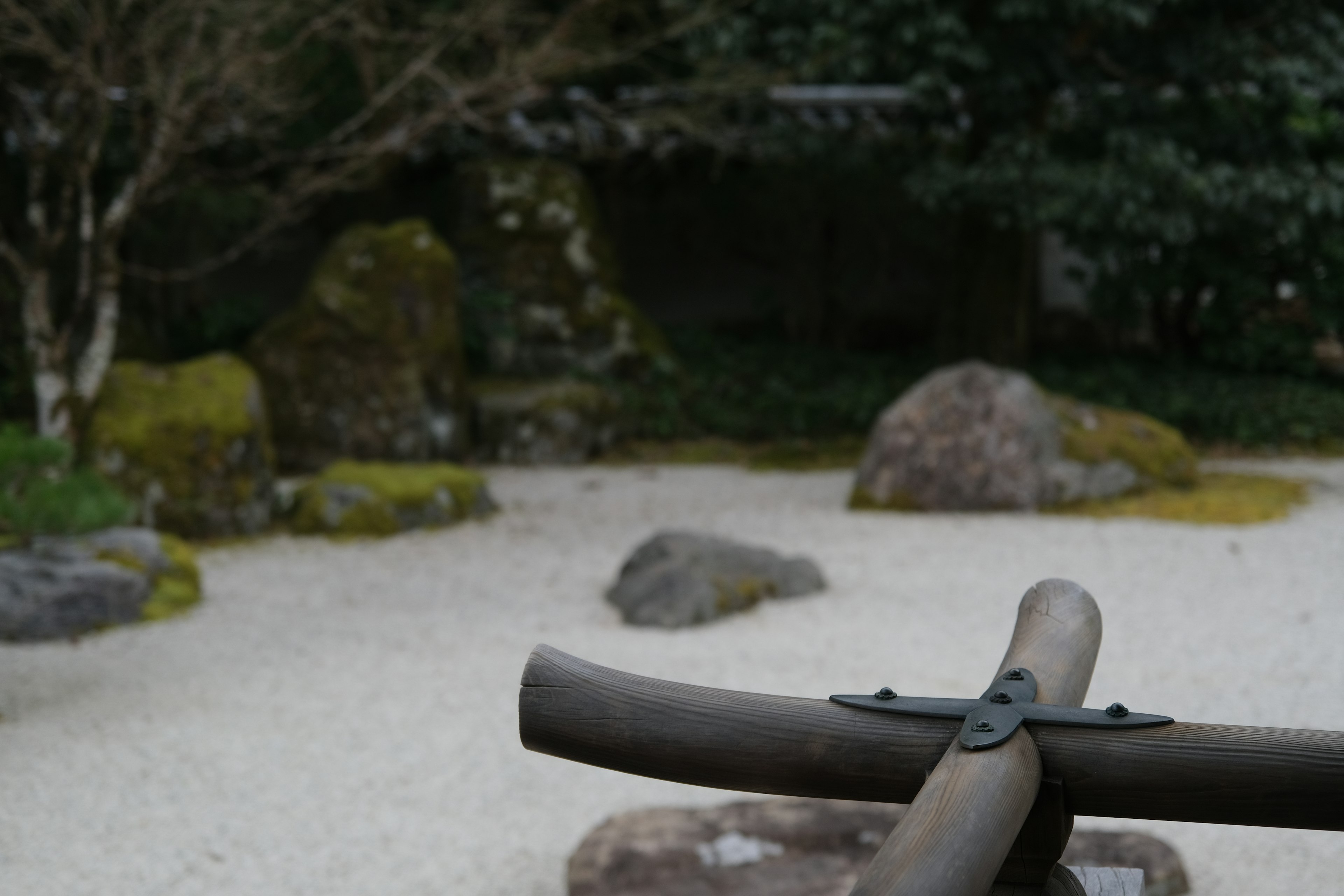 静かな日本庭園の一部で竹の水汲み器と白砂の庭石が見える