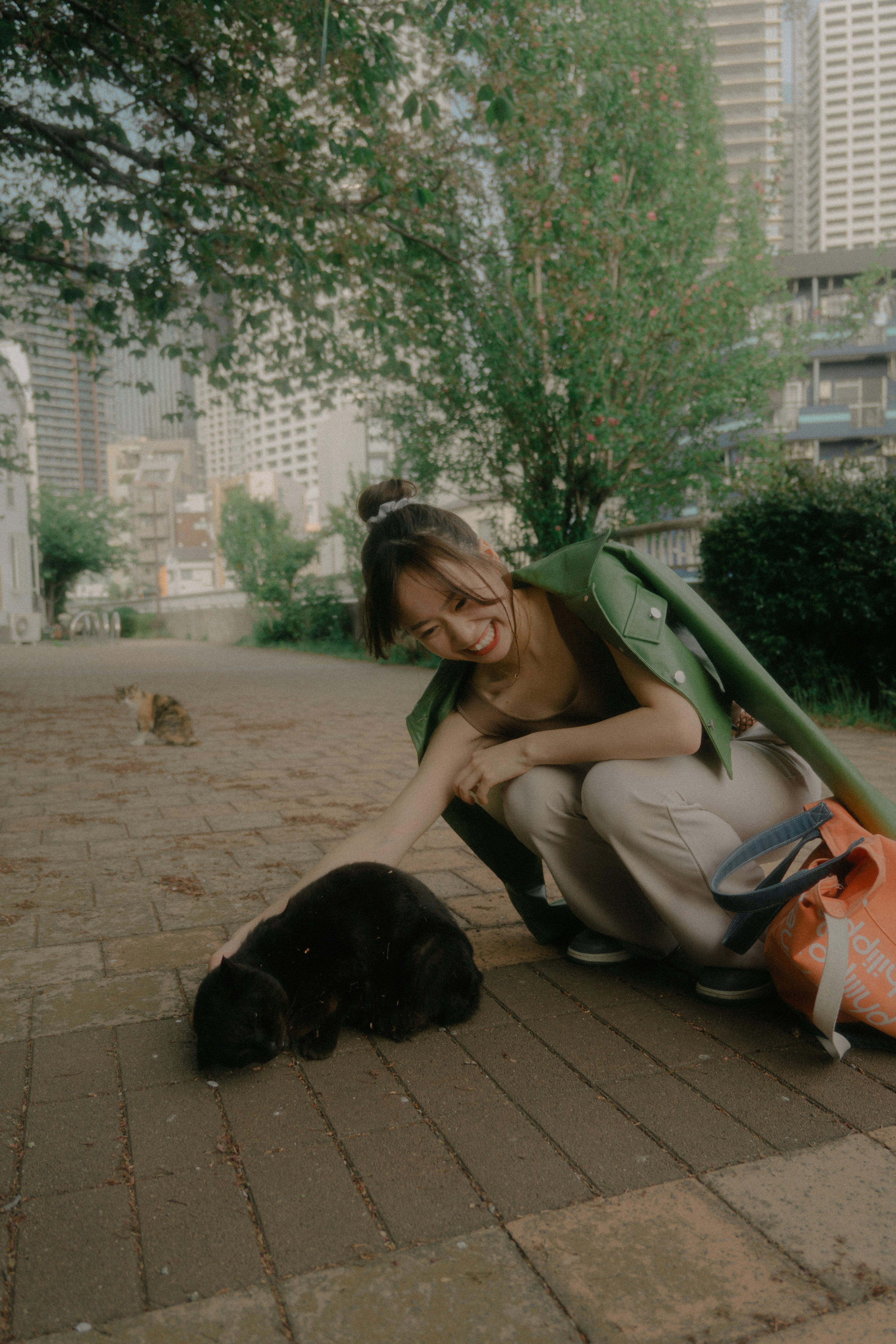 A woman petting a dog in a park with greenery in the background