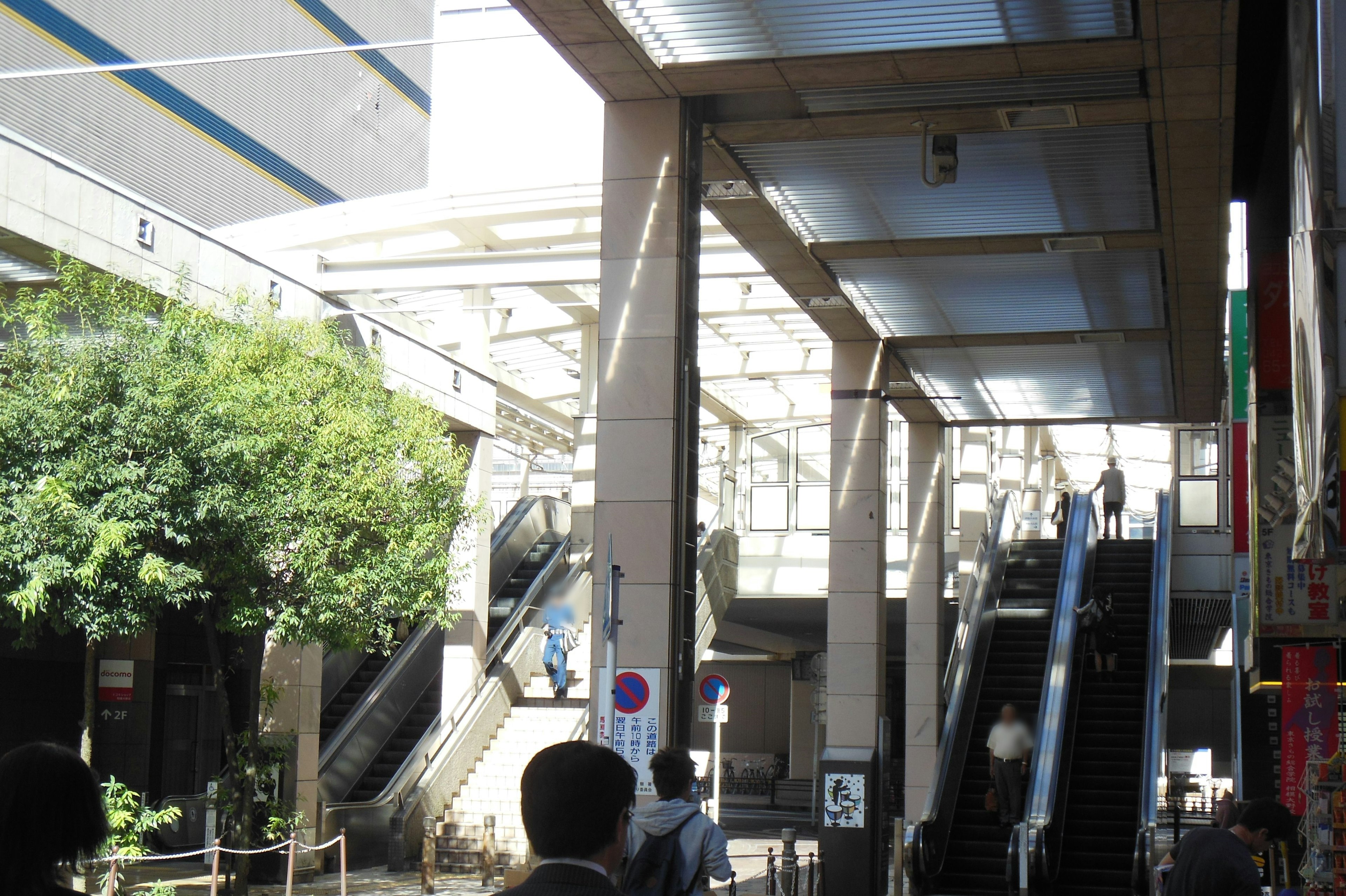 Vista exterior que muestra escaleras mecánicas y vegetación en un entorno urbano