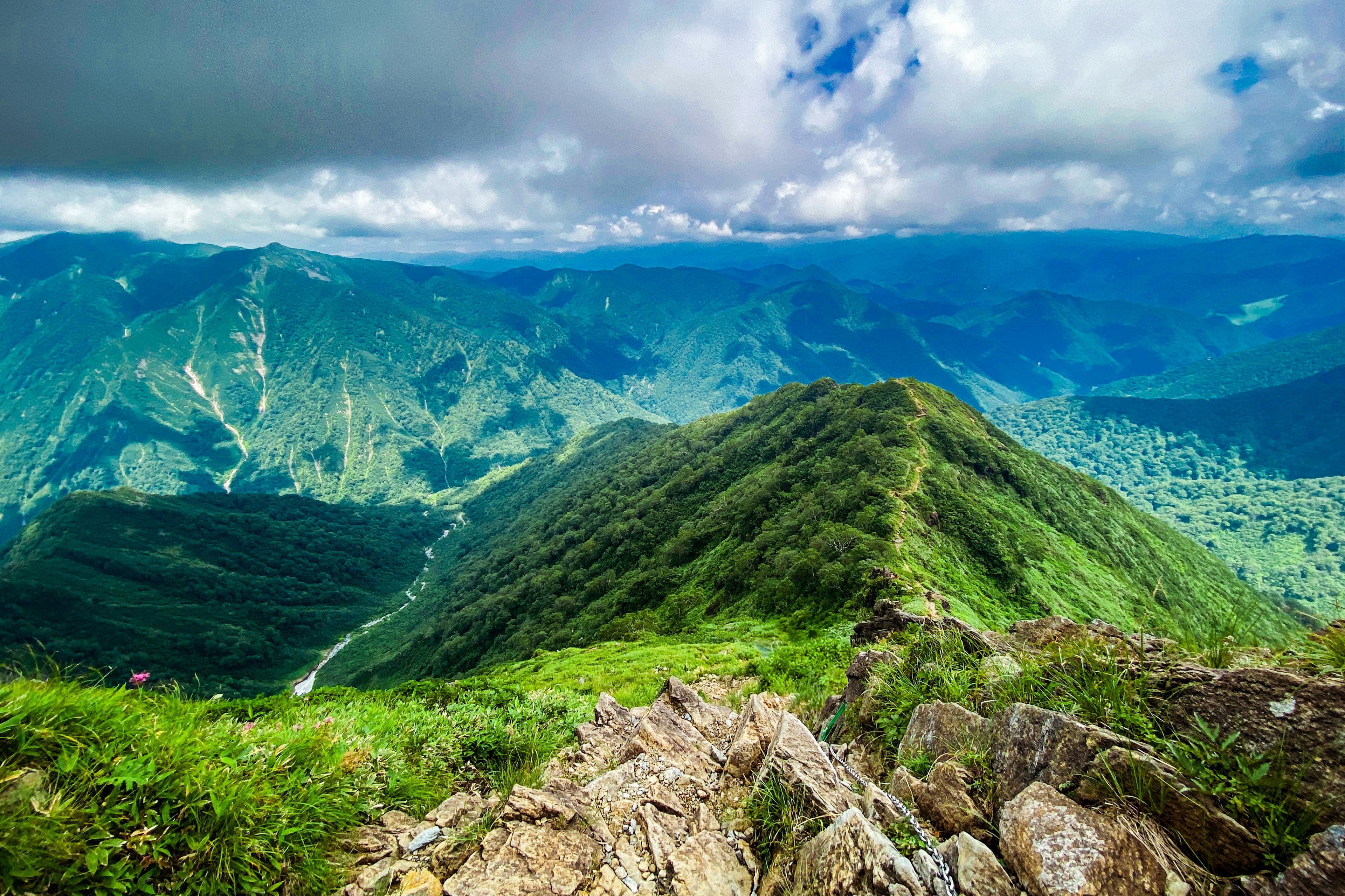 从山顶俯瞰的壮观景色，绿意盎然的山丘和蓝天