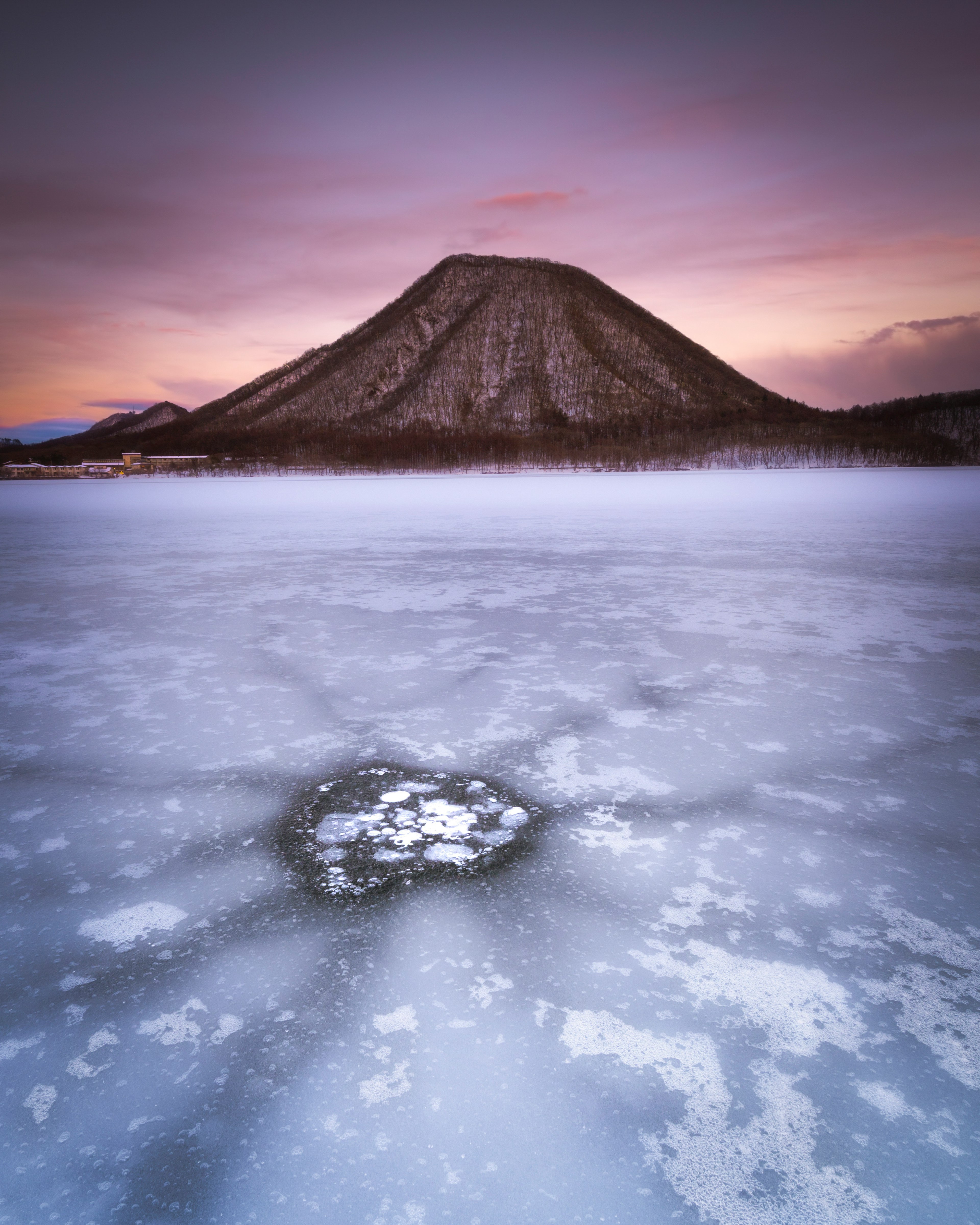 氷で覆われた湖とその向こうにある山の風景