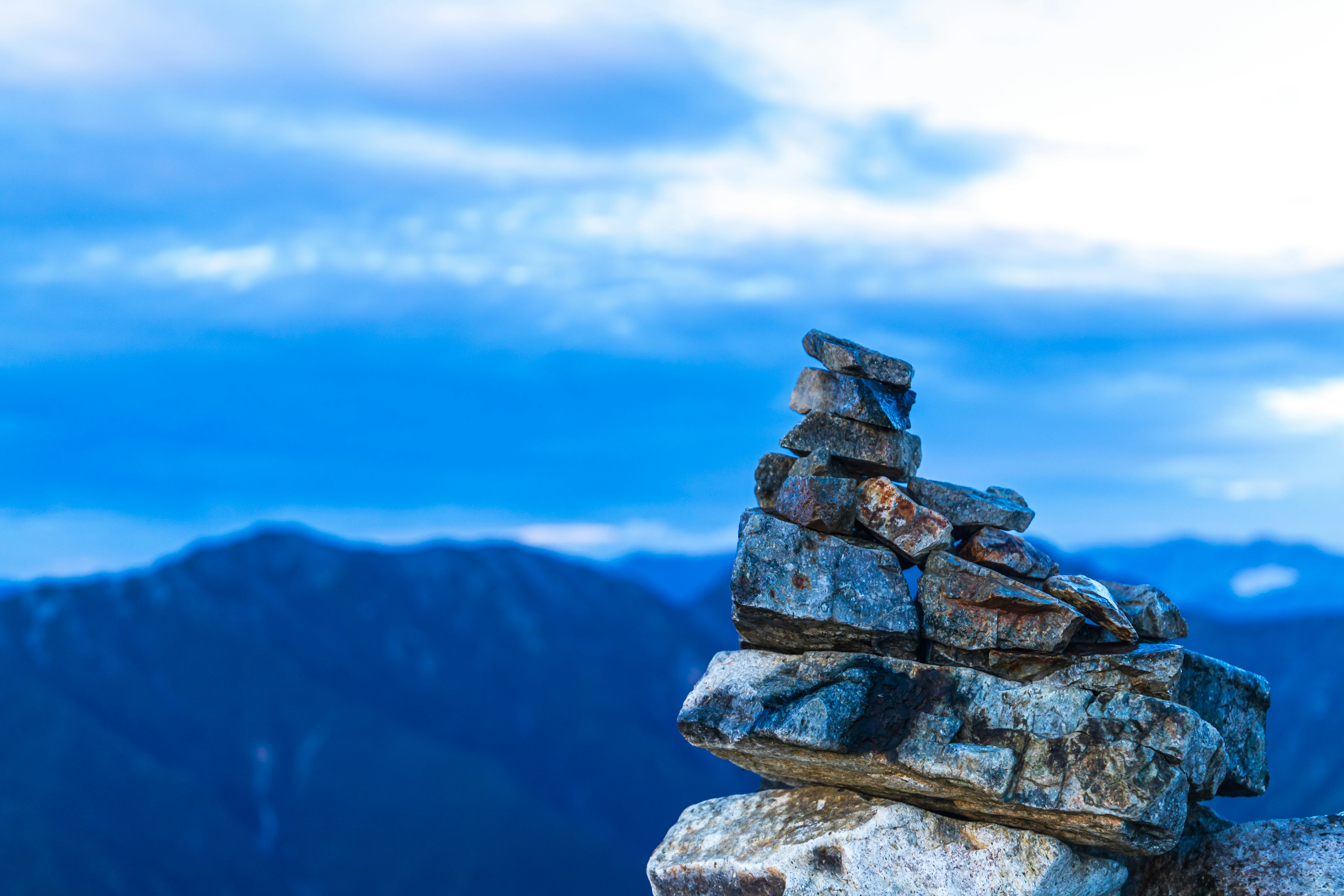 Stack of rocks against a backdrop of blue sky and mountains