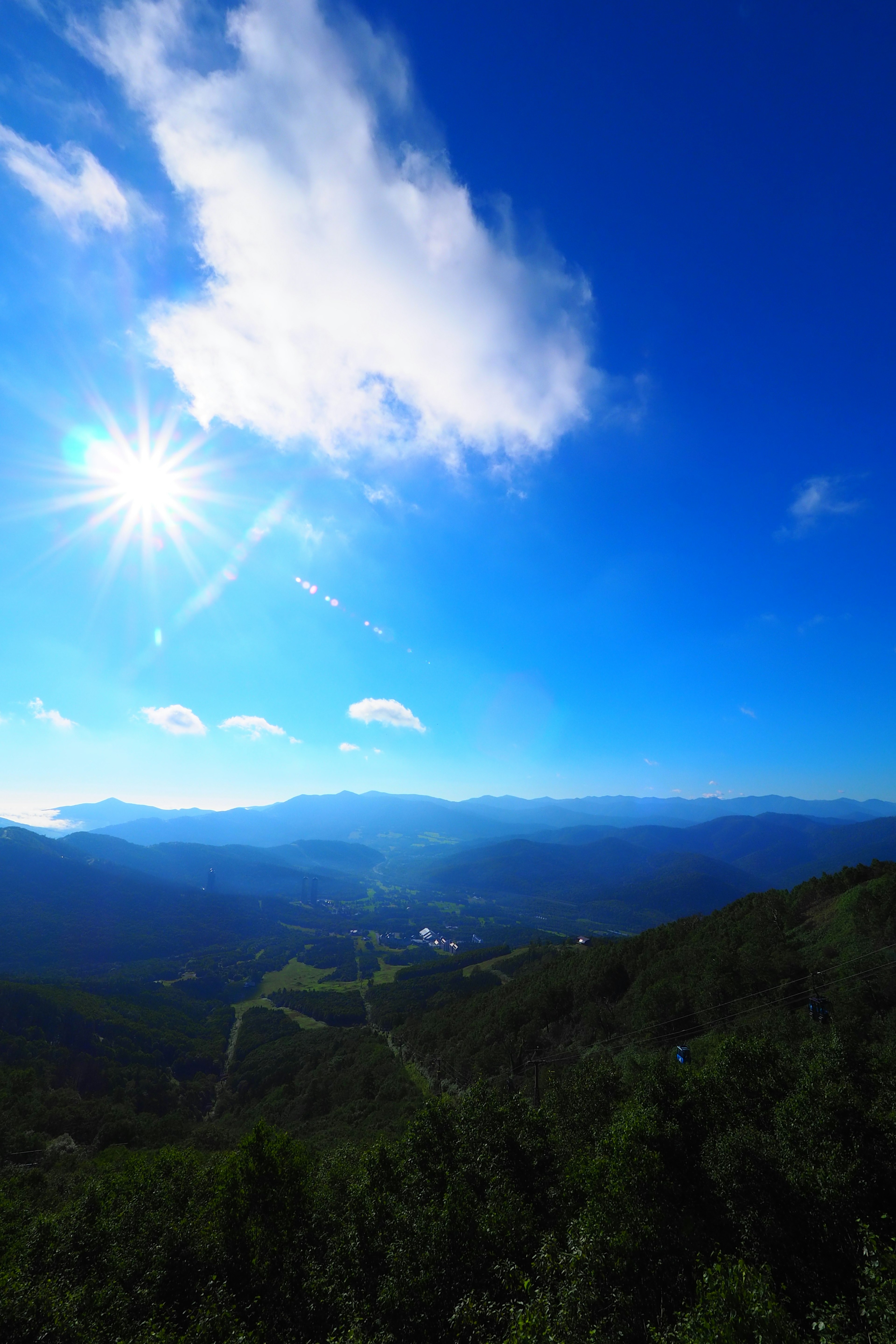 Panoramablick auf Berge unter einem strahlend blauen Himmel mit leuchtender Sonne