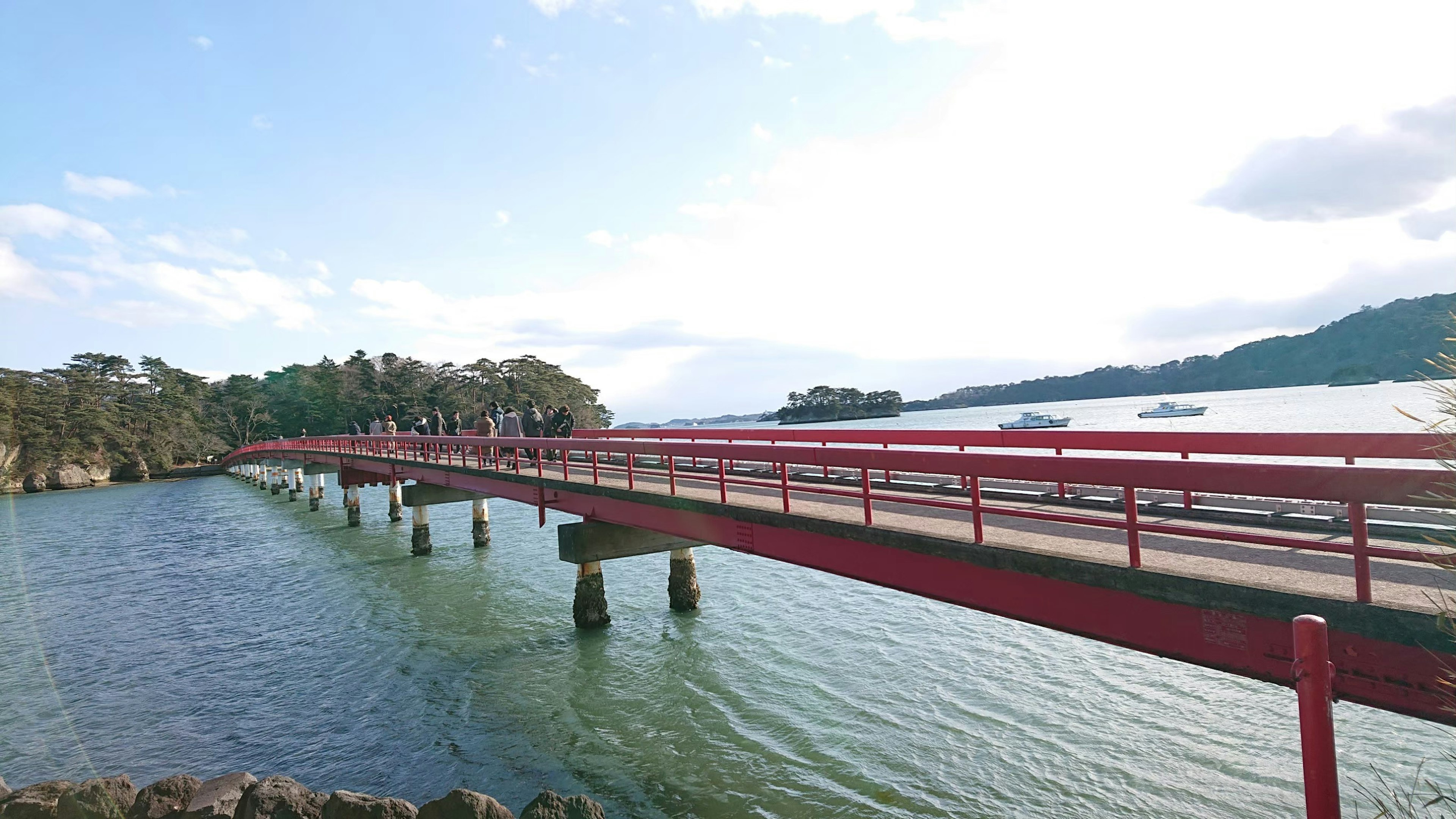 赤い橋が水面に架かり周囲の自然が広がる風景