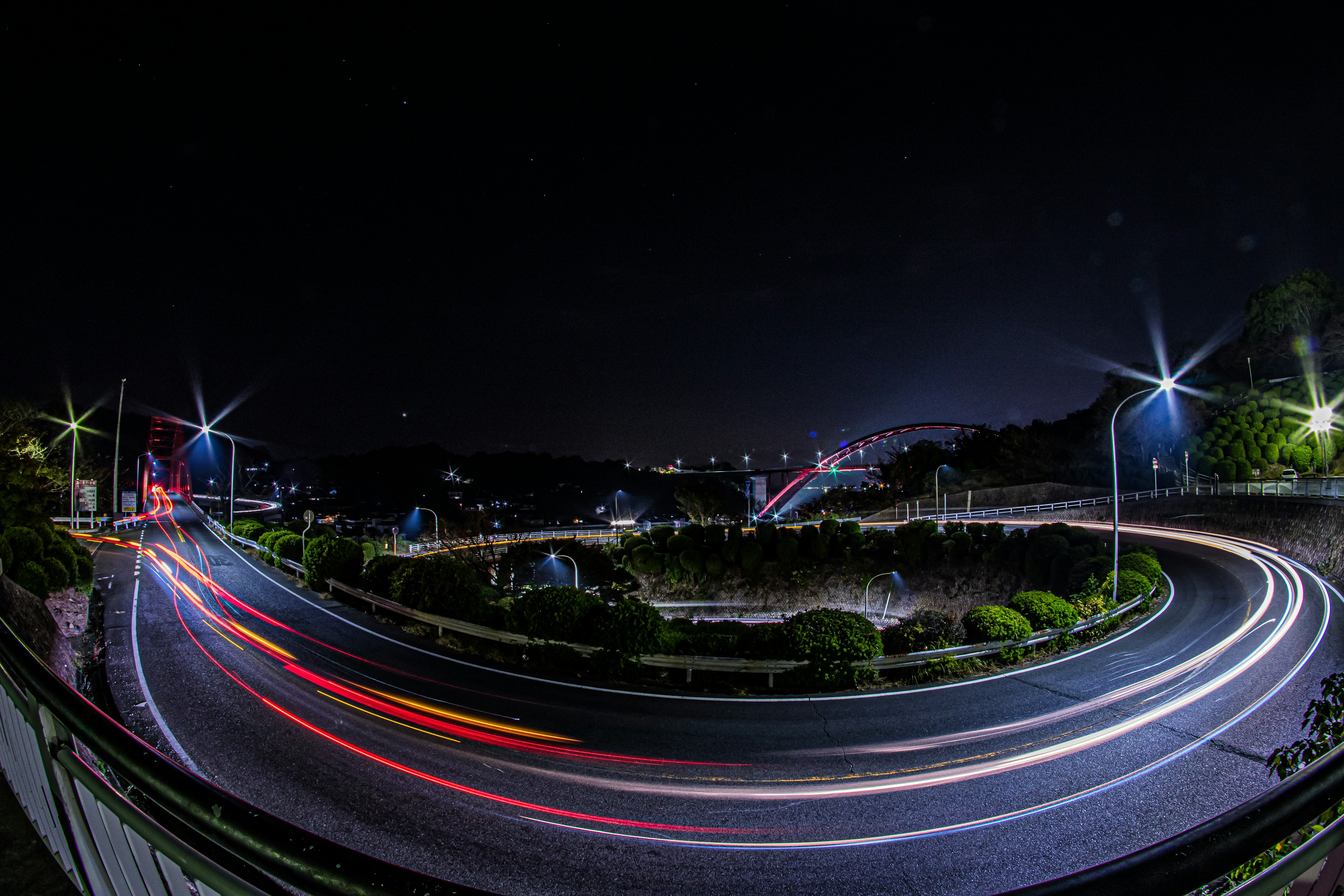 Night view of a winding road with light trails from passing cars