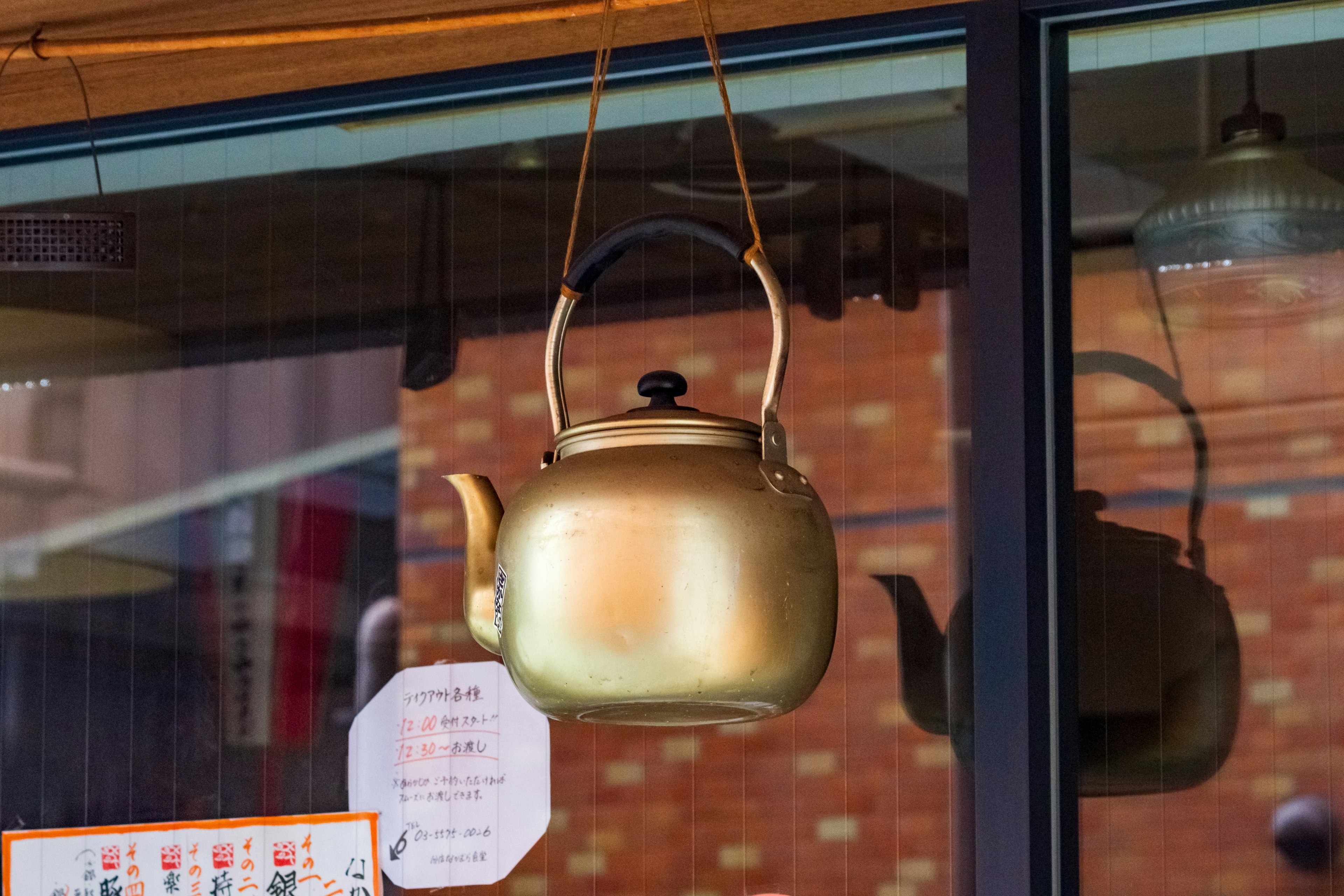 A golden teapot hanging in a window