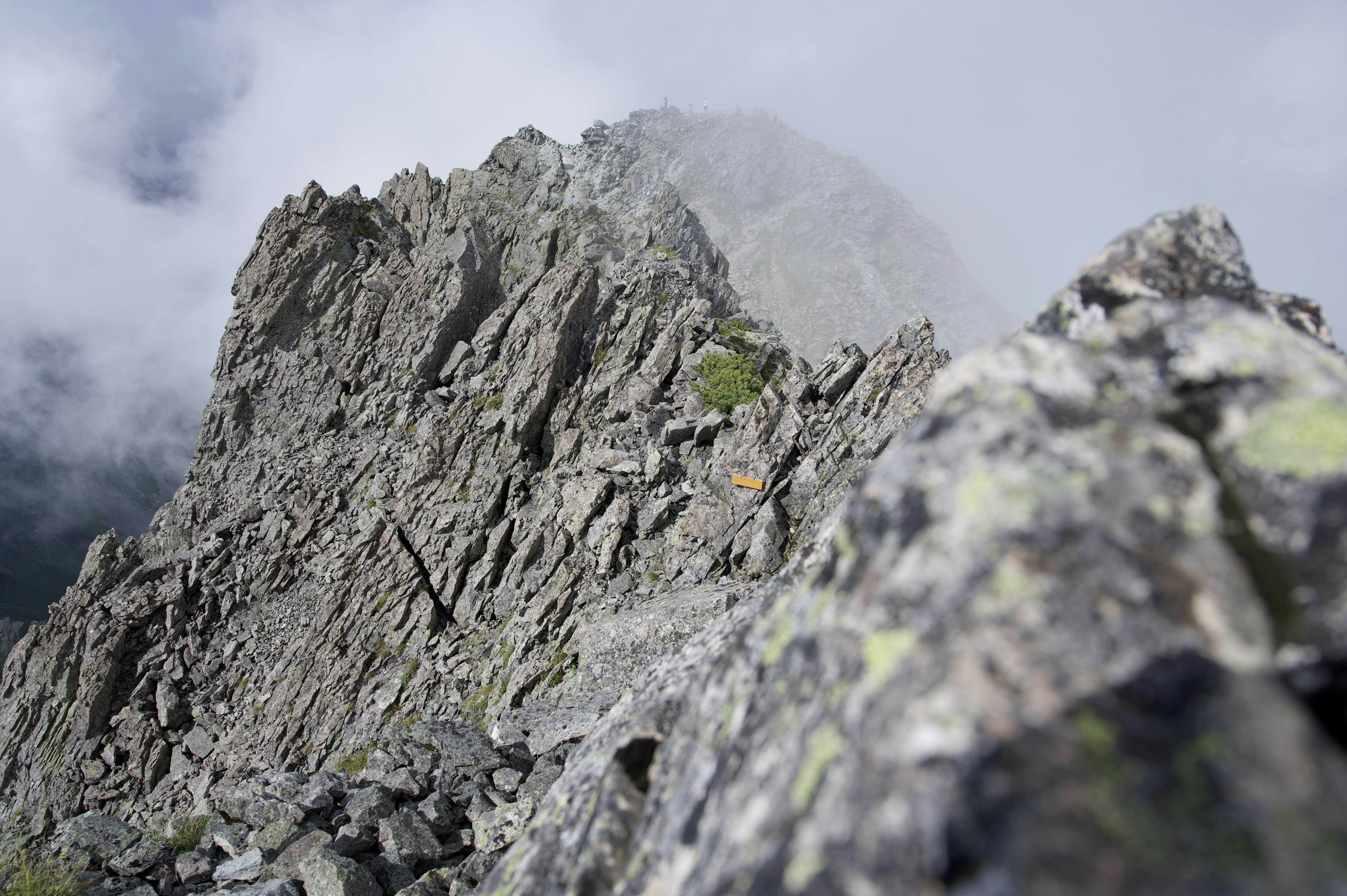 Primer plano de una cresta montañosa rocosa envuelta en niebla que muestra texturas rugosas y un paisaje dramático