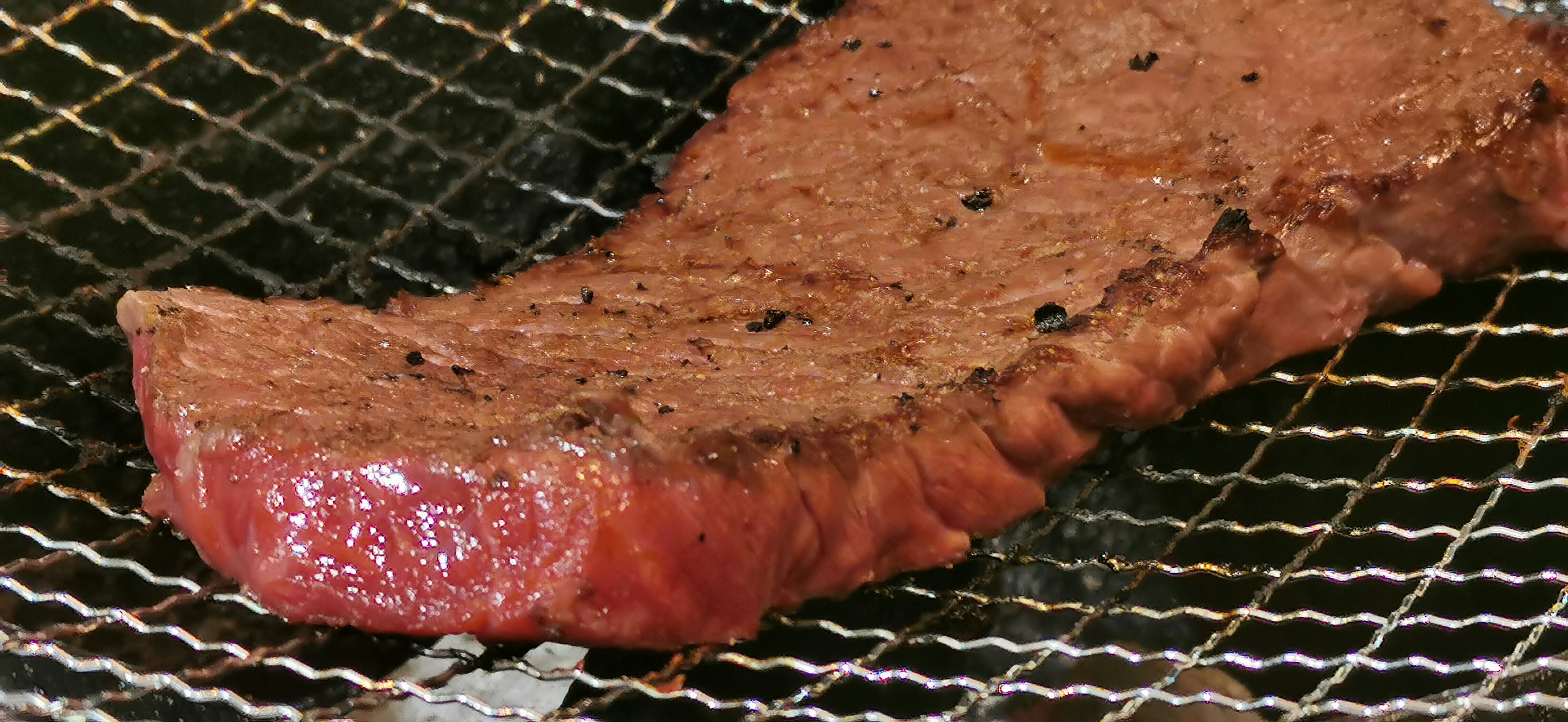 Grilled slice of meat resting on a wire rack