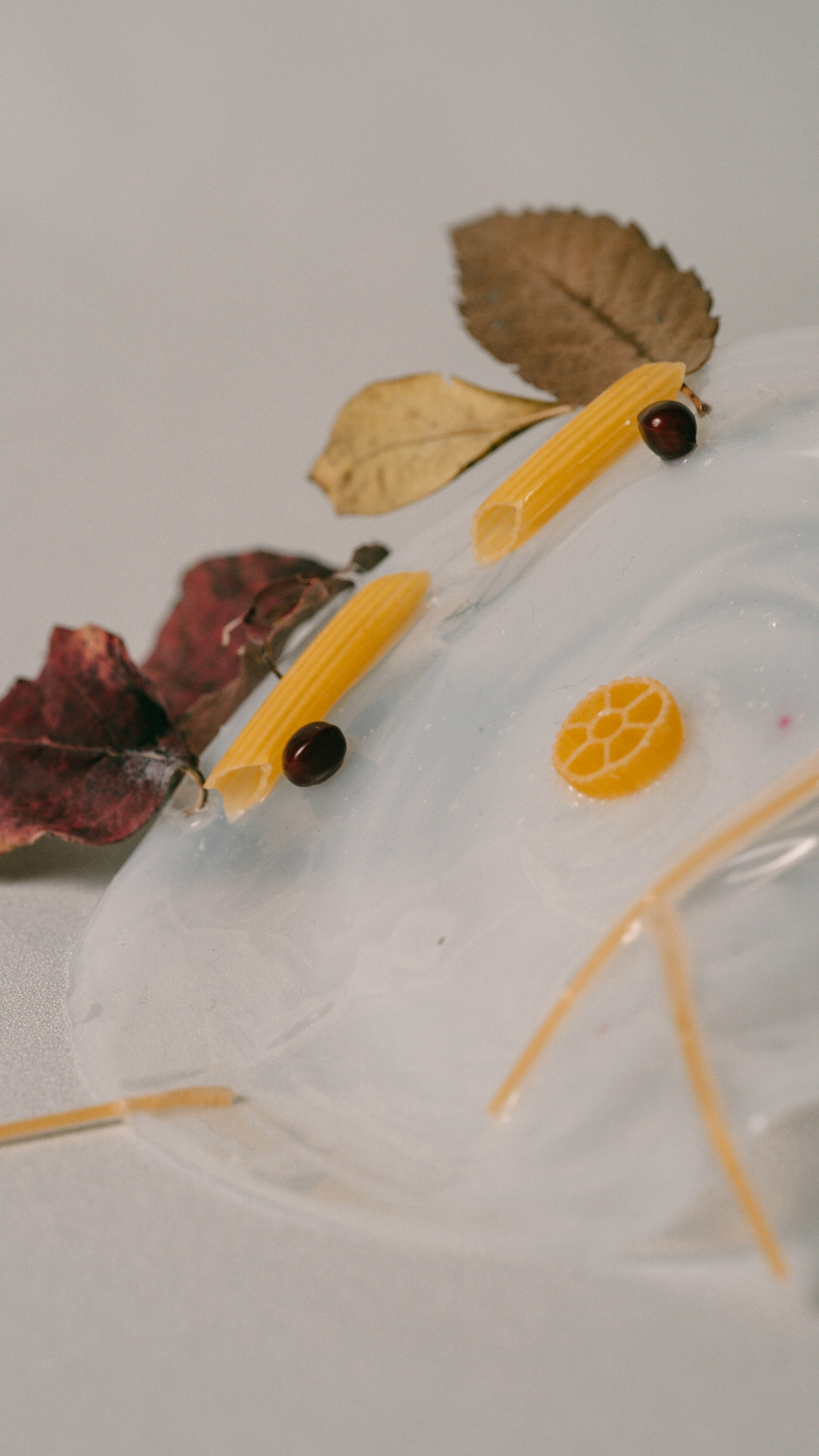 Artistic face made with yellow pasta and leaves on a white background