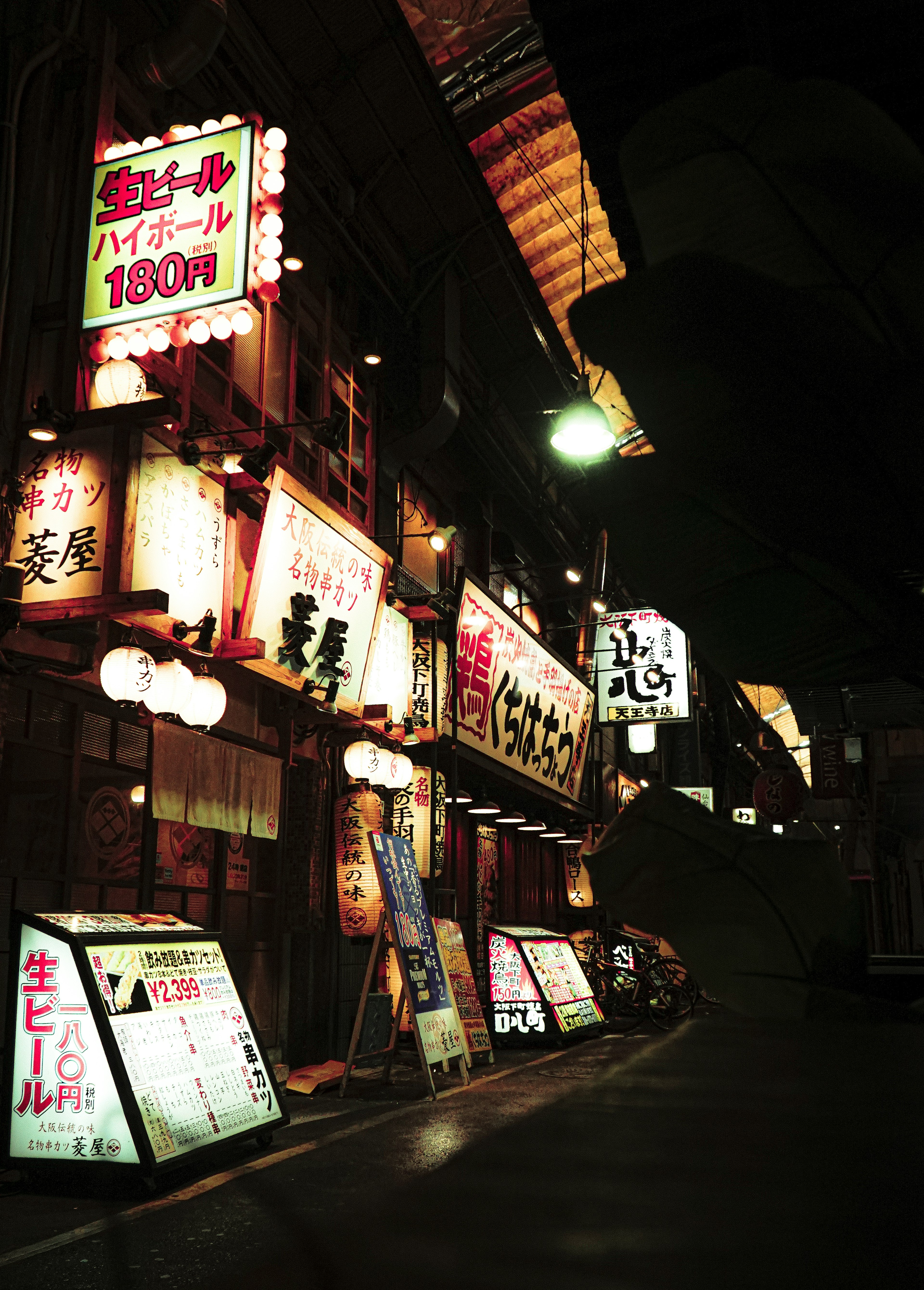 Neon signs and storefronts of restaurants in a Japanese street at night