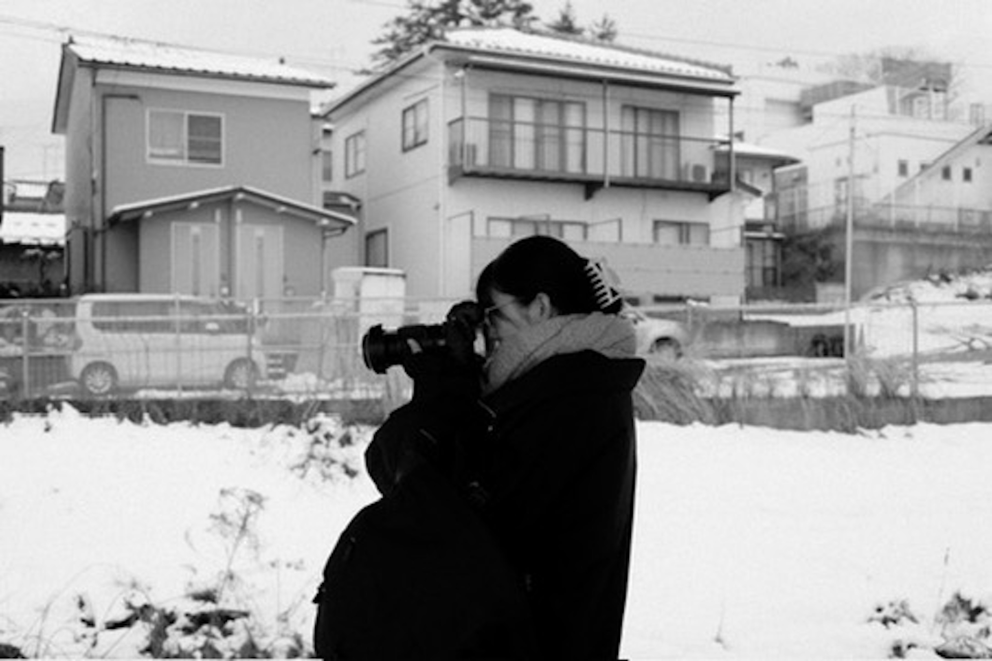 雪に覆われた風景の中でカメラを構える人物のモノクロ写真