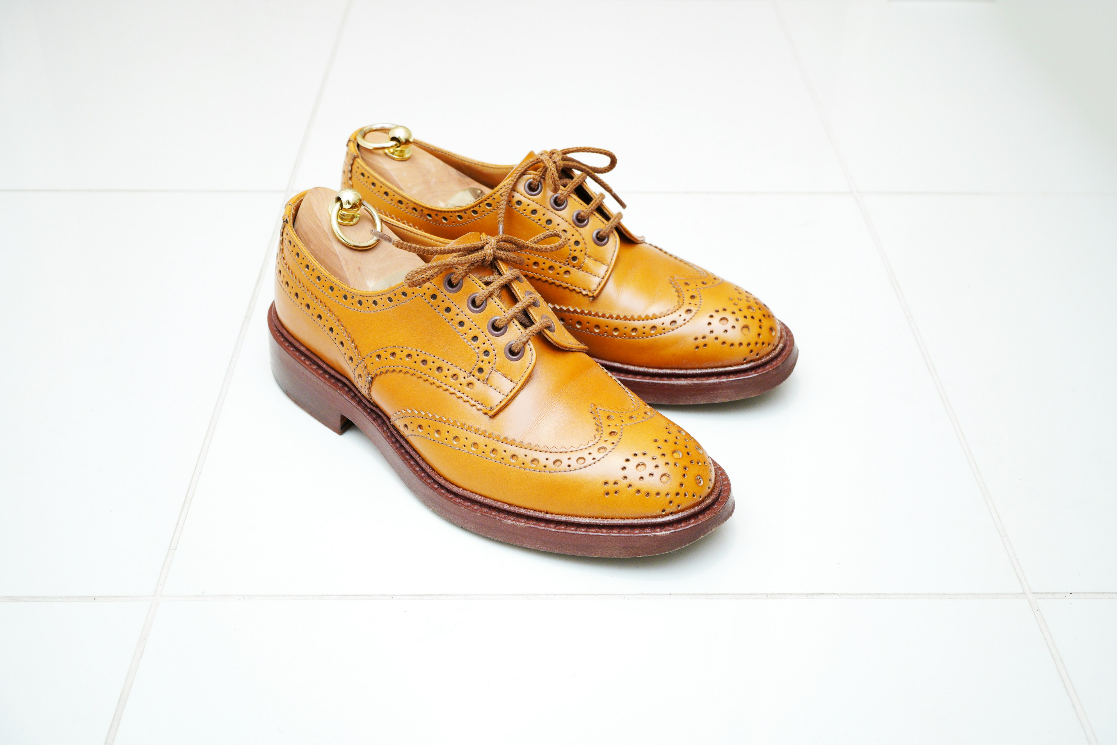 Brown leather dress shoes with intricate detailing on a white background