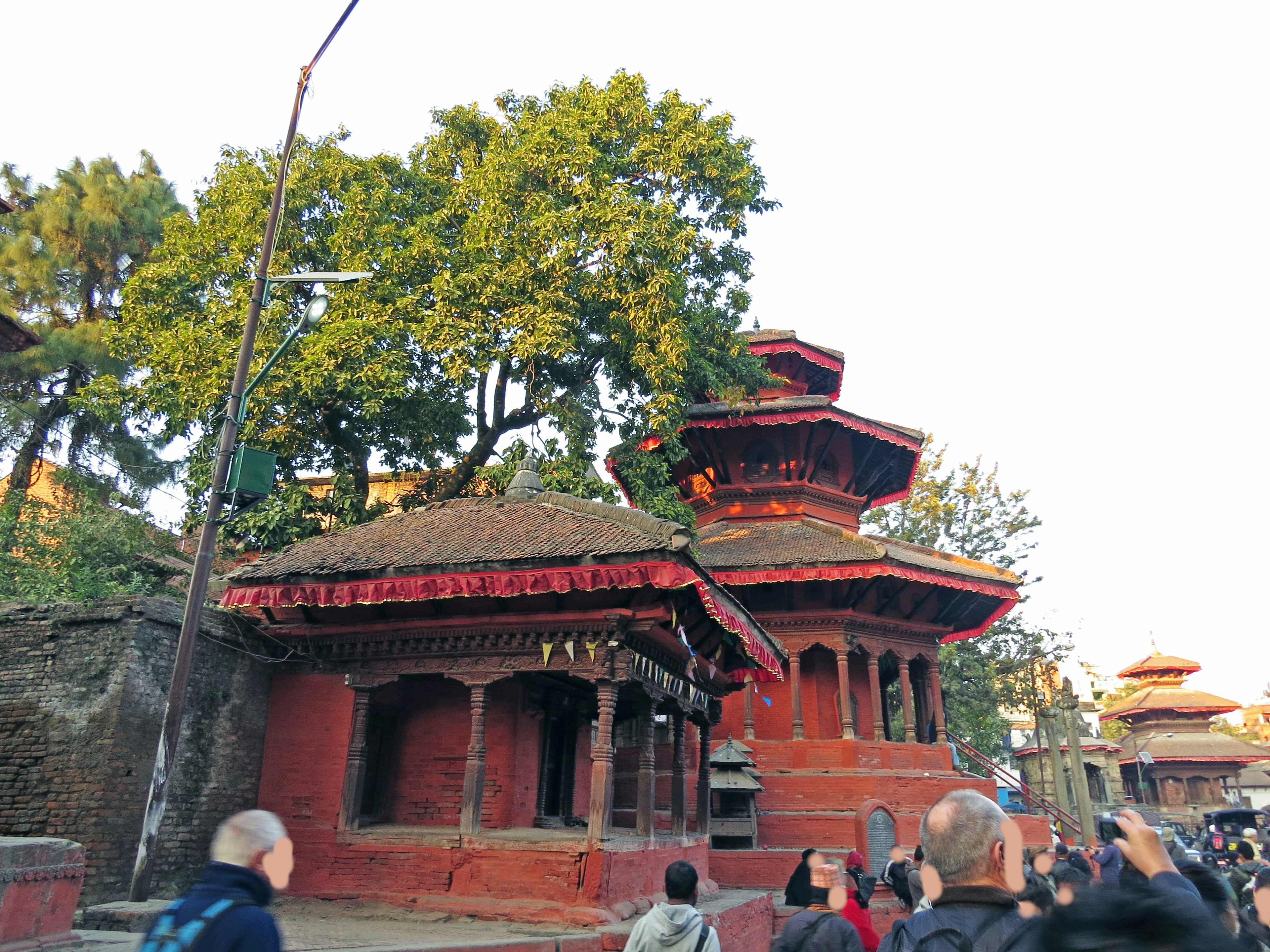 Tempio rosso nepalese con alberi verdi sullo sfondo