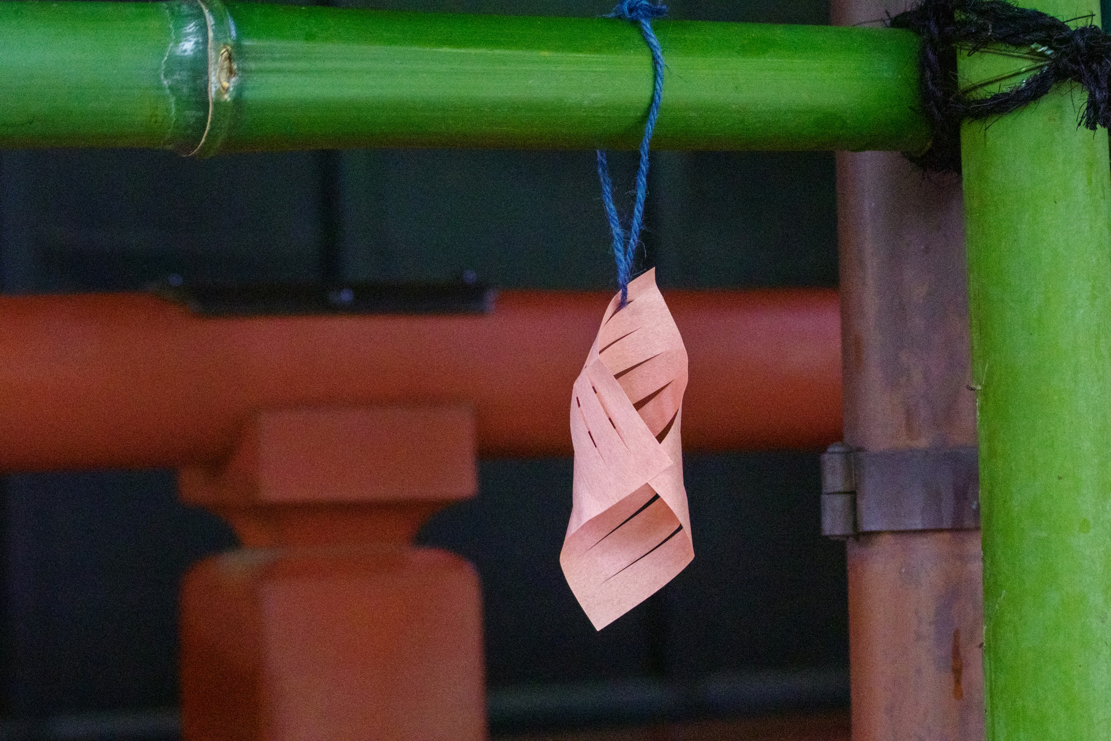 Un trozo de papel naranja colgando de una vara de bambú verde