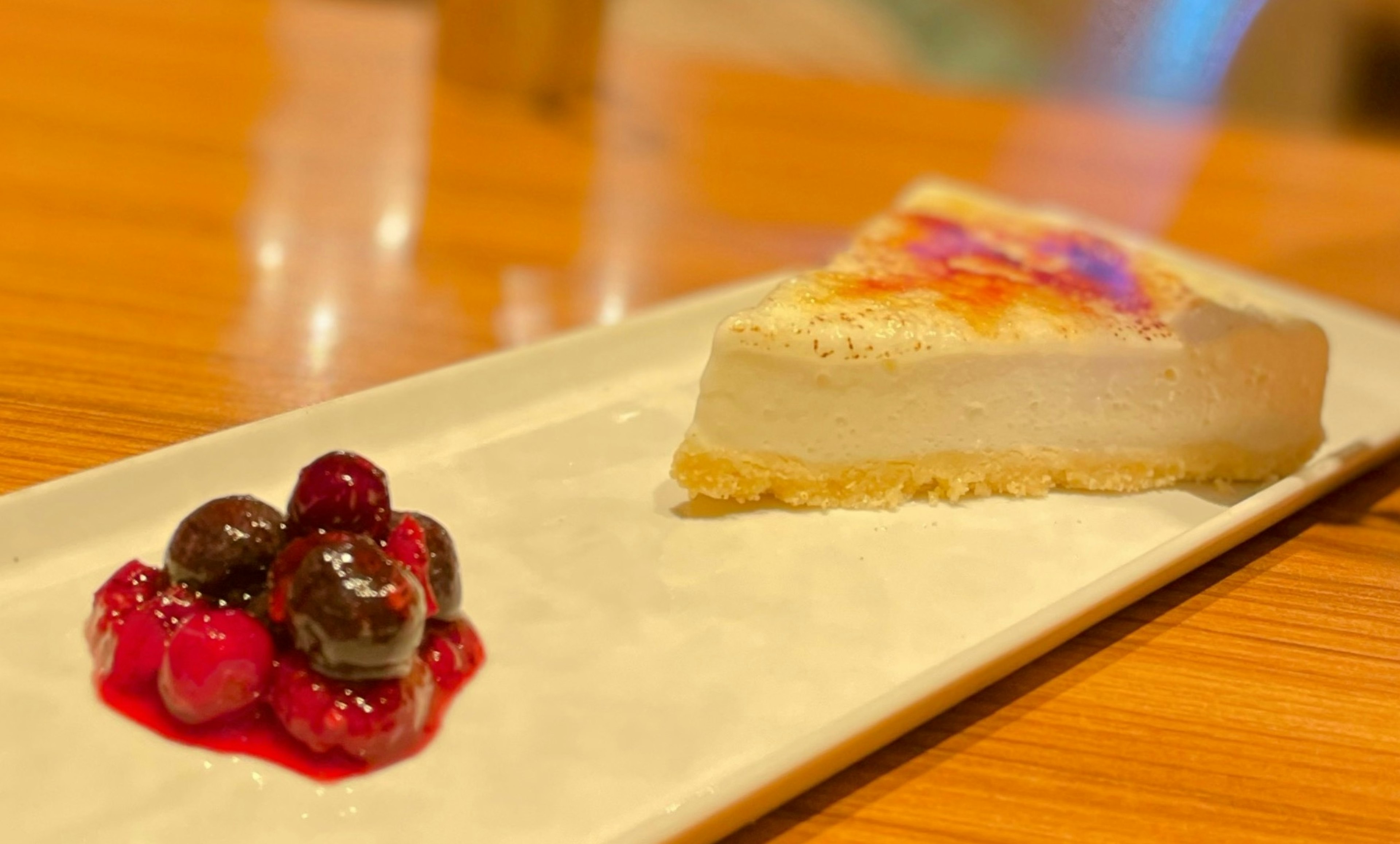 Slice of creamy cheesecake with berry sauce on a plate