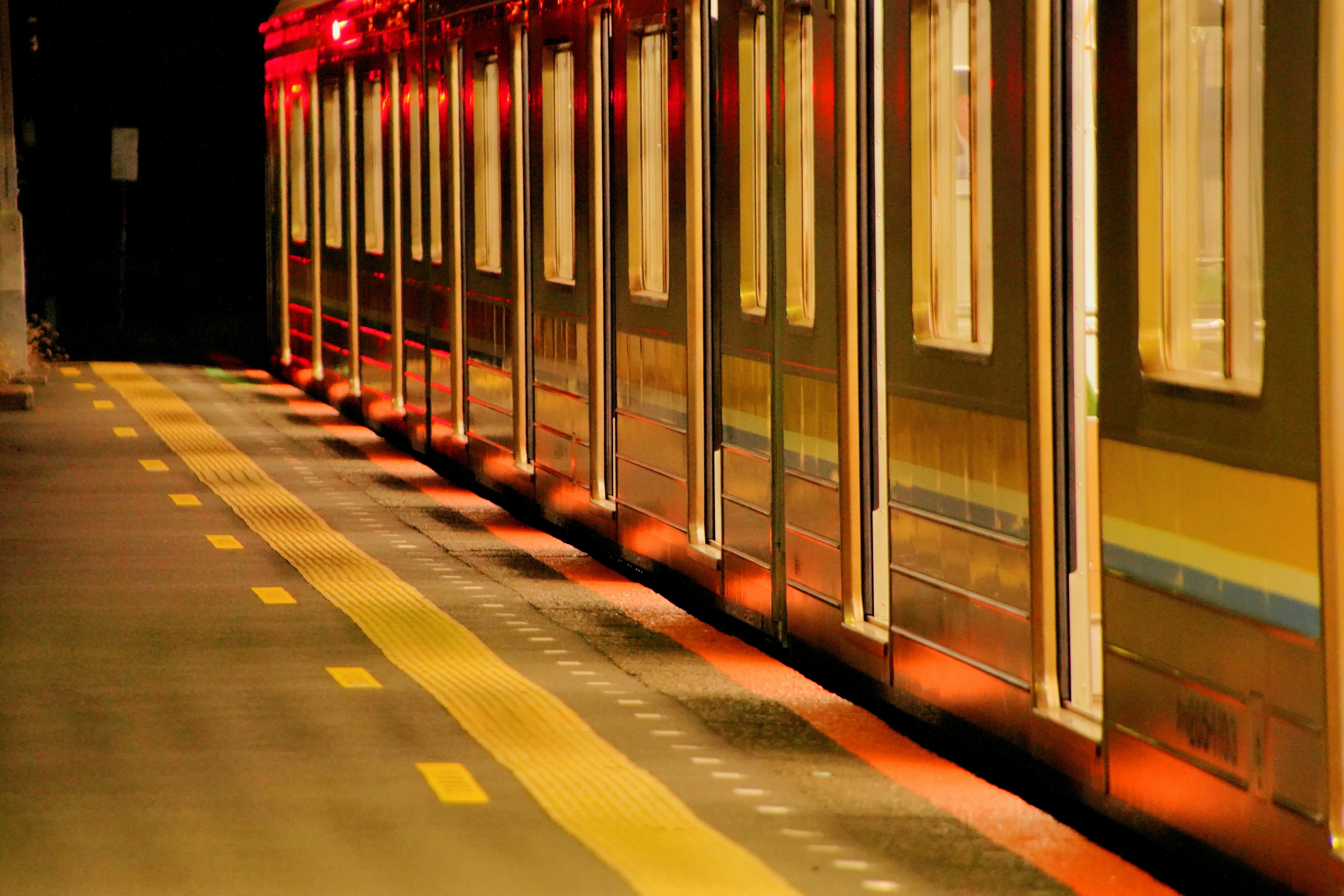 Train cars illuminated by red lights at night in a station