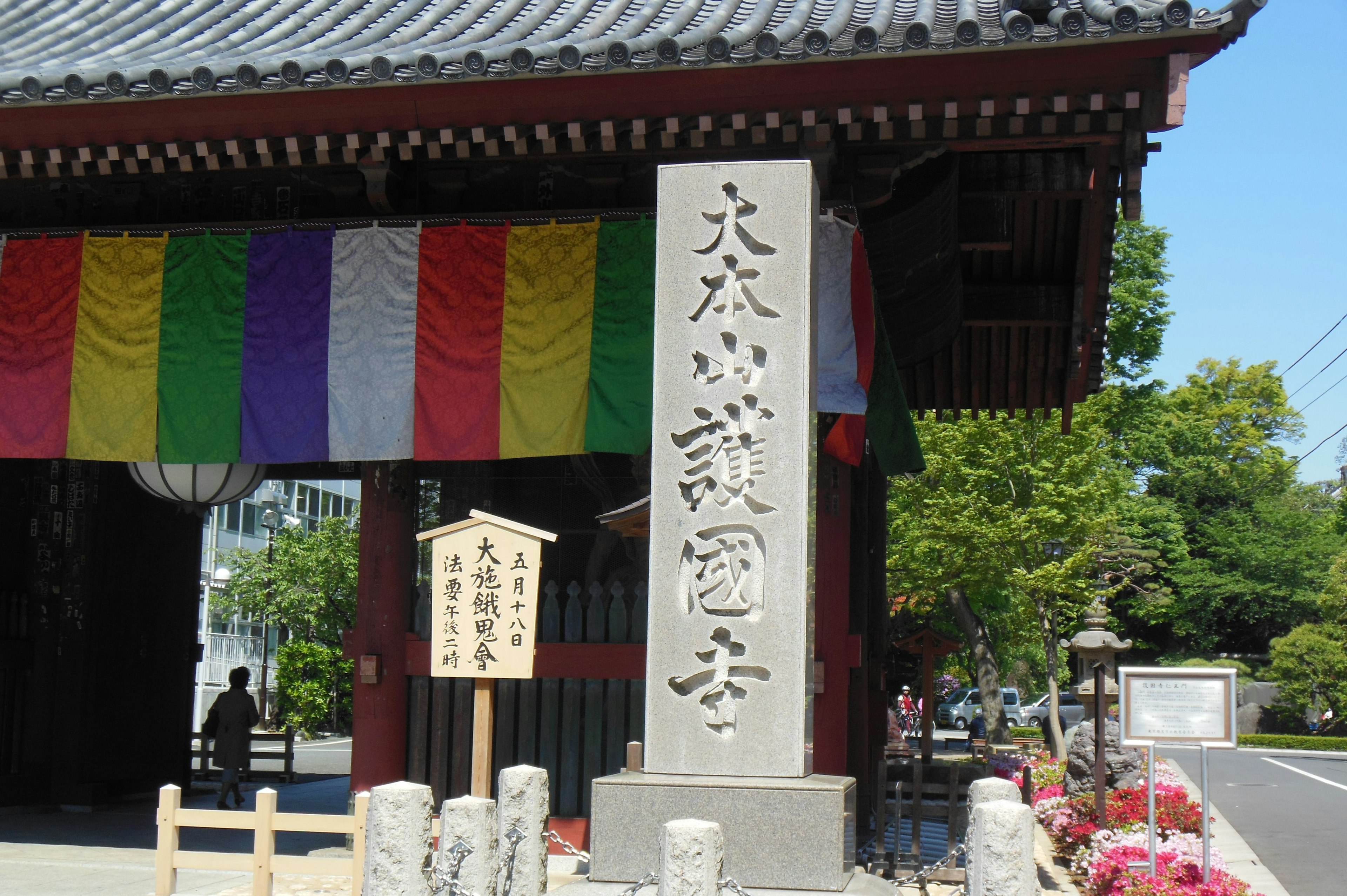 Entrance of a temple with a large stone pillar and colorful drapes