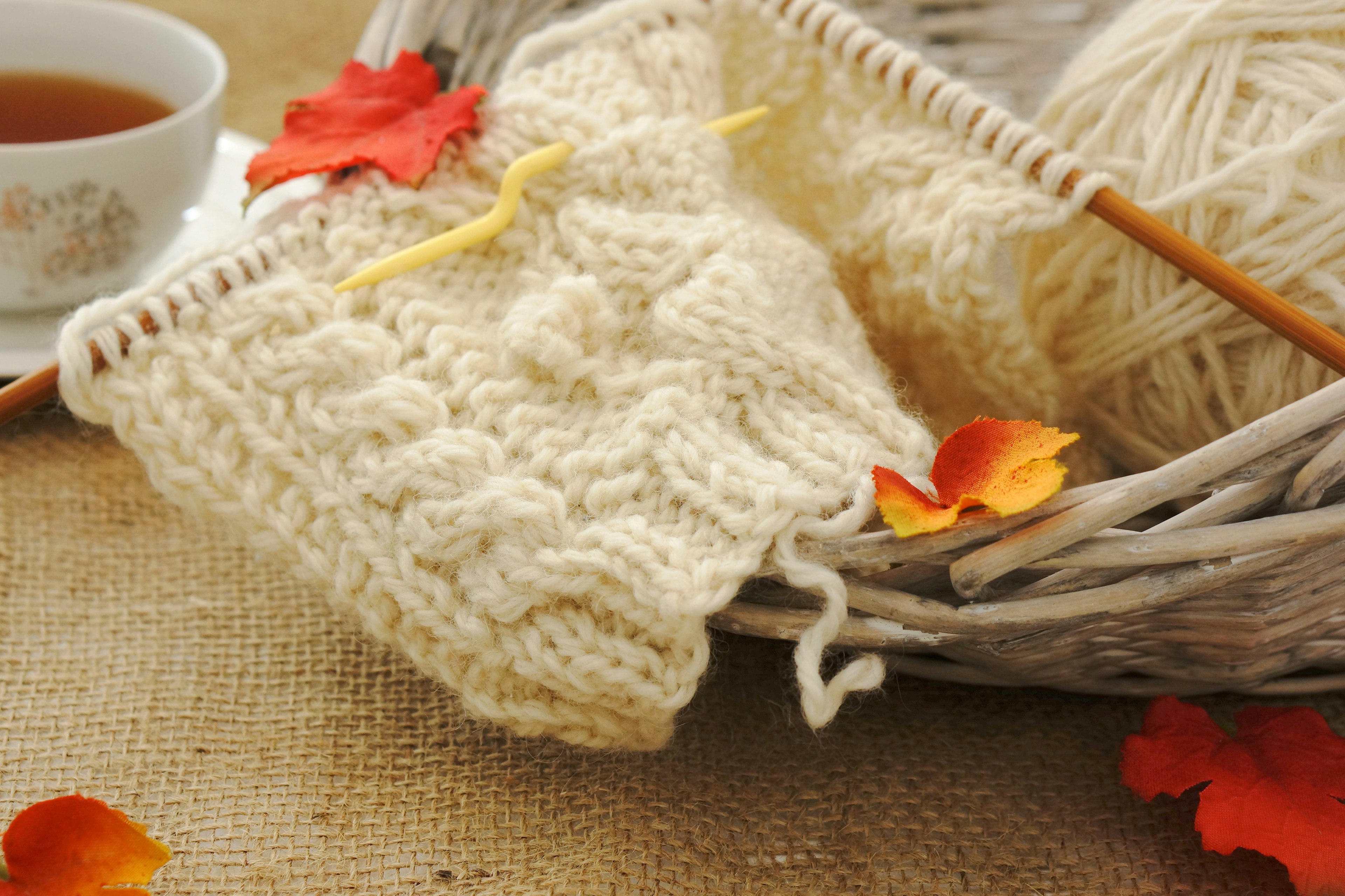 Knitted cream yarn piece with tea cup and autumn leaves