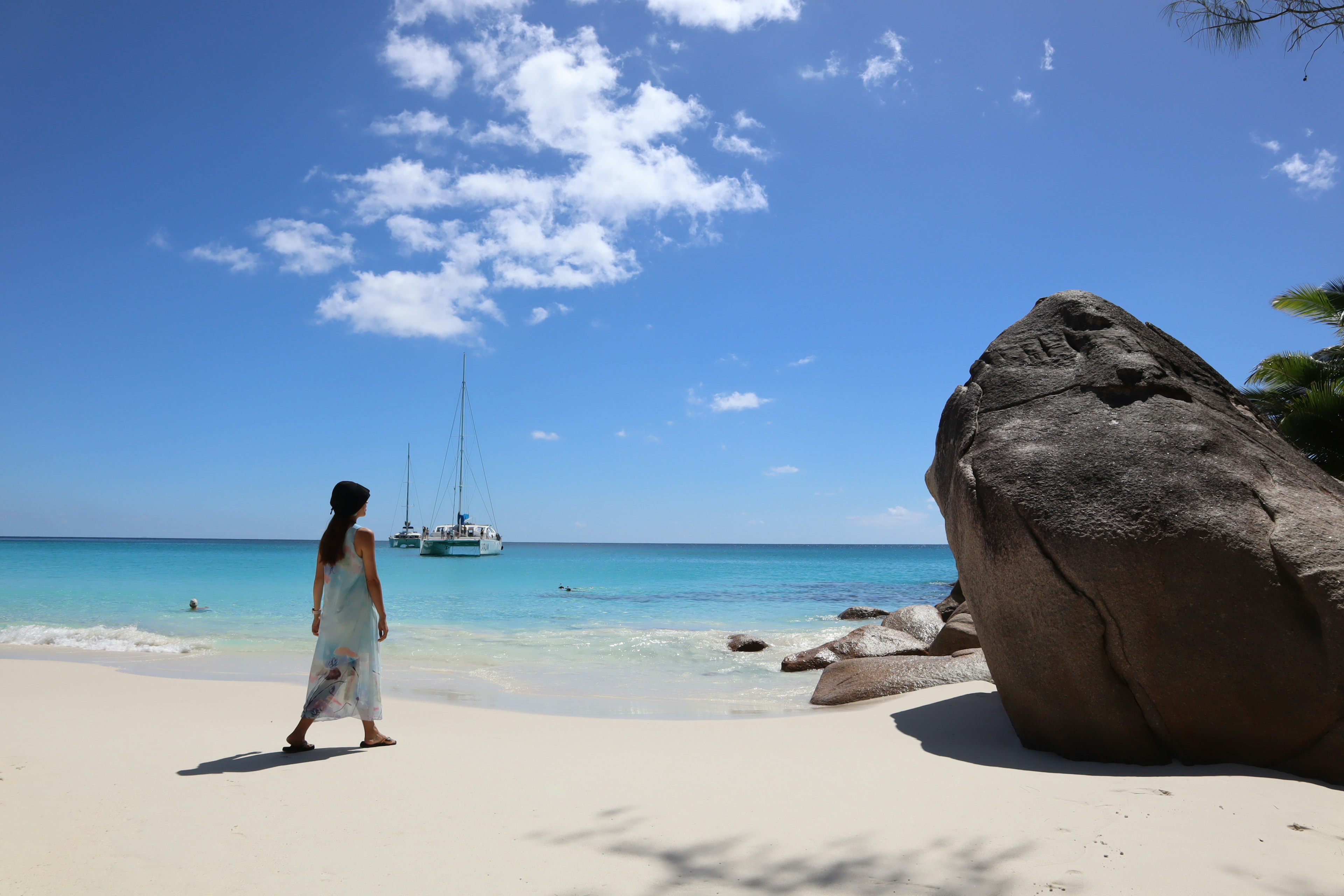 Una mujer caminando en una playa con agua azul y arena blanca