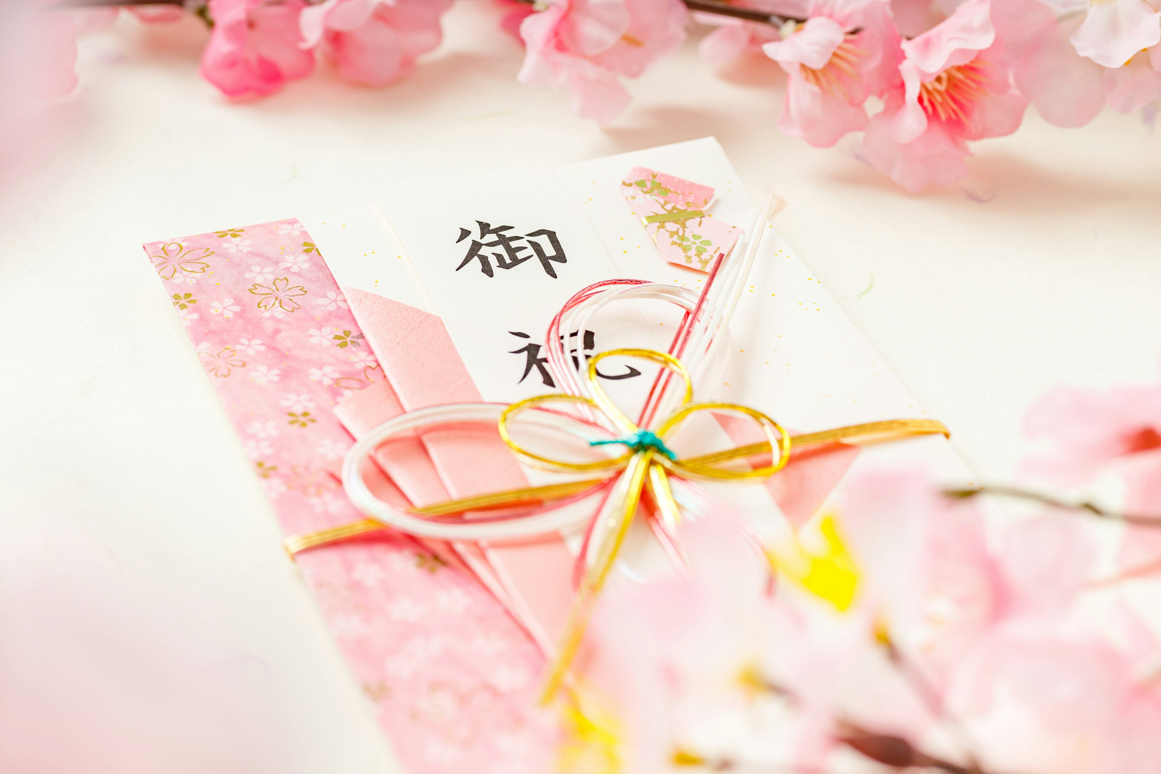 Envelope and card decorated with cherry blossoms and golden ribbon