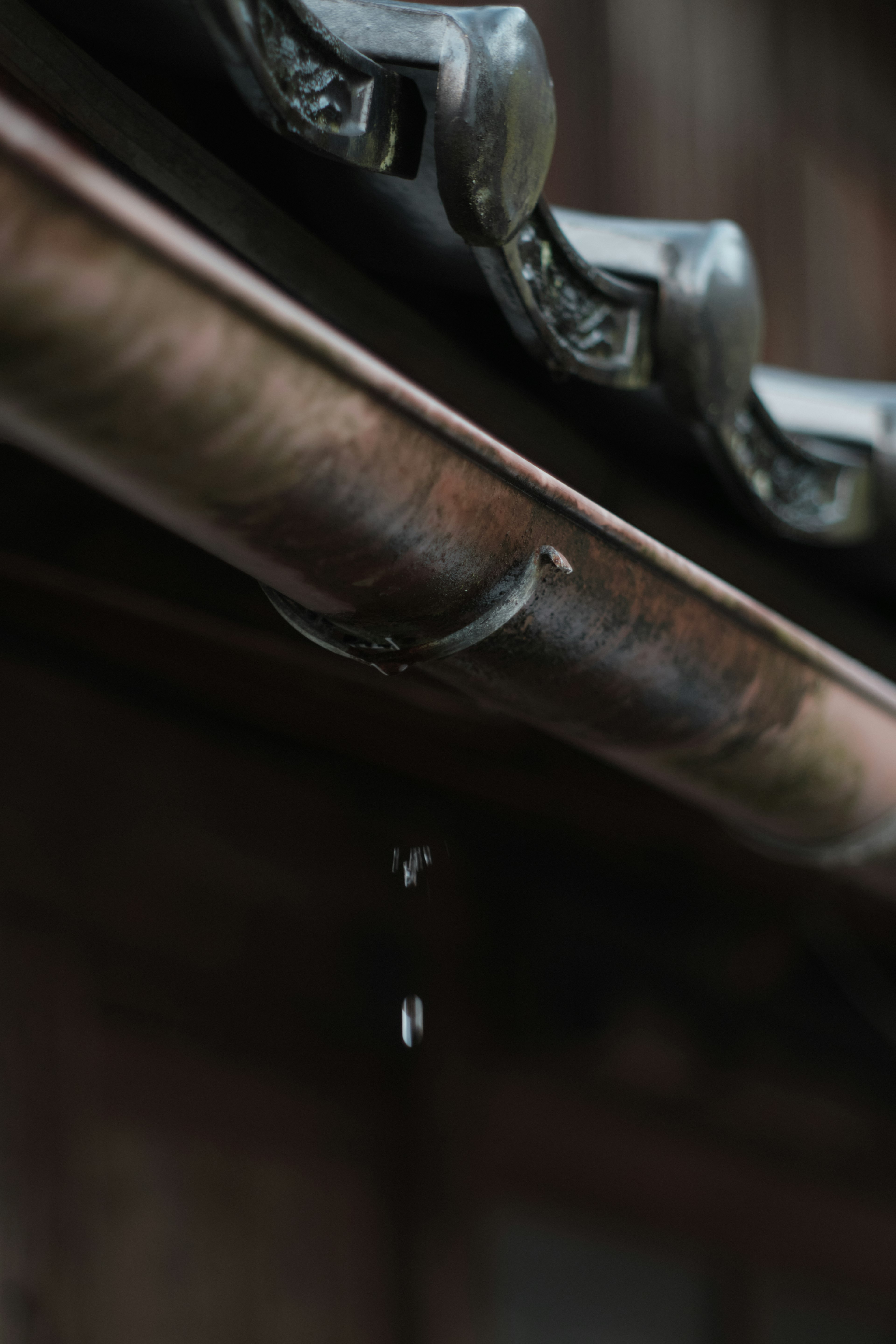 Close-up of a traditional roof gutter with rainwater dripping