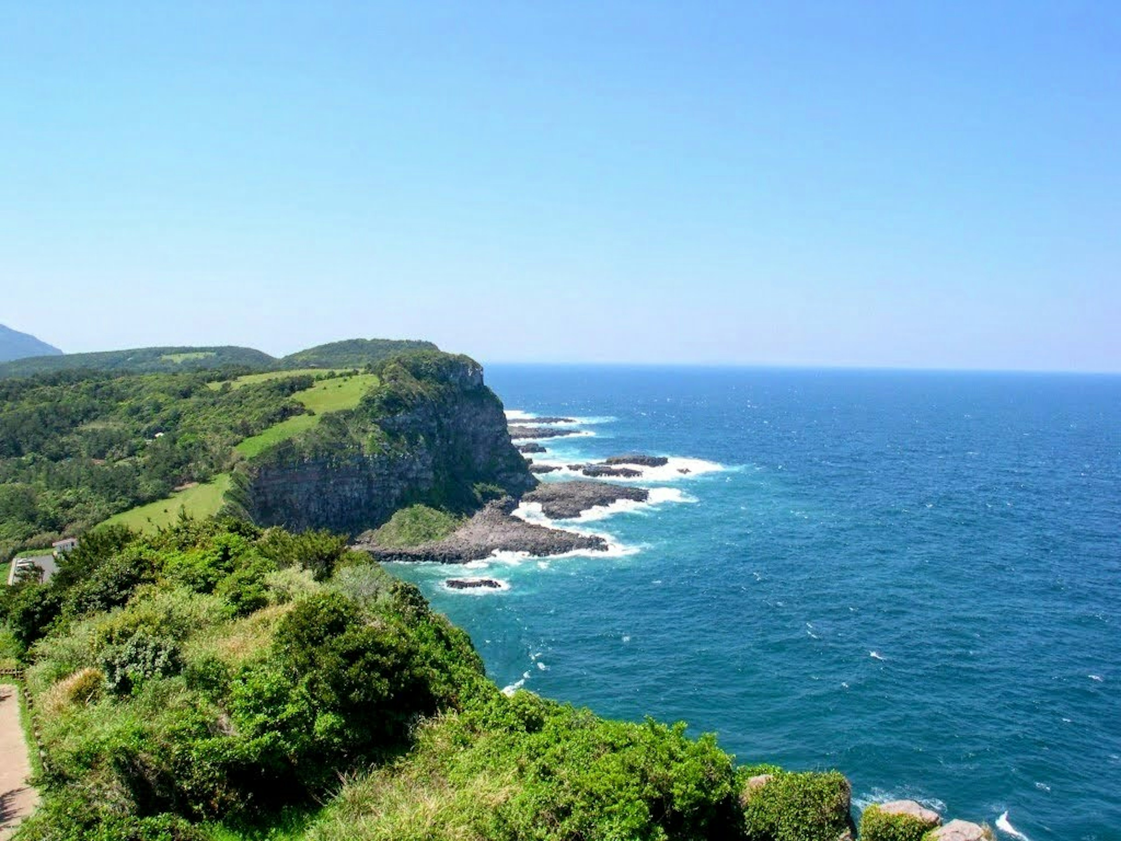 Scenic view of blue ocean and lush green cliffs