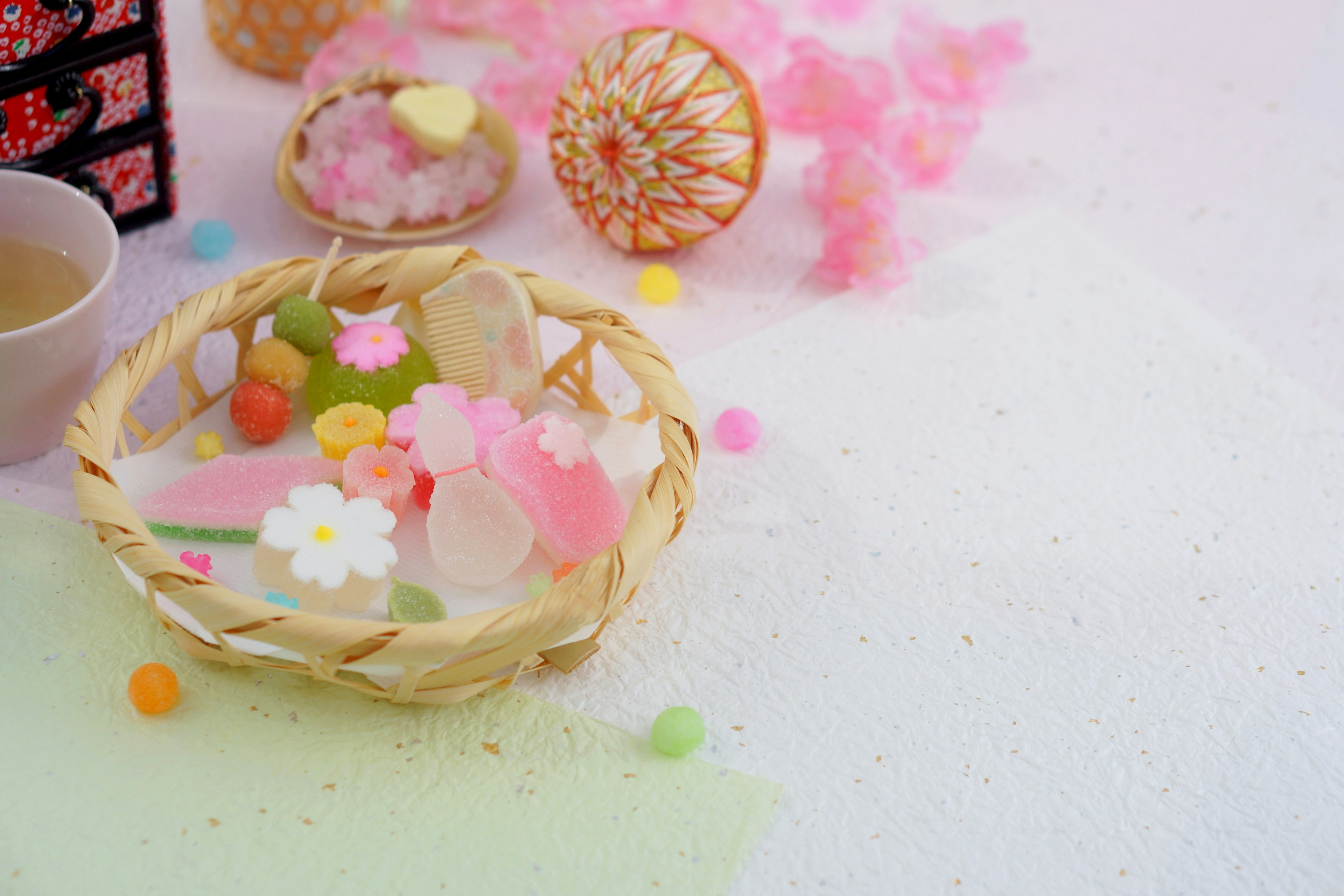 Des bonbons japonais colorés et des fleurs de cerisier disposés dans un petit panier