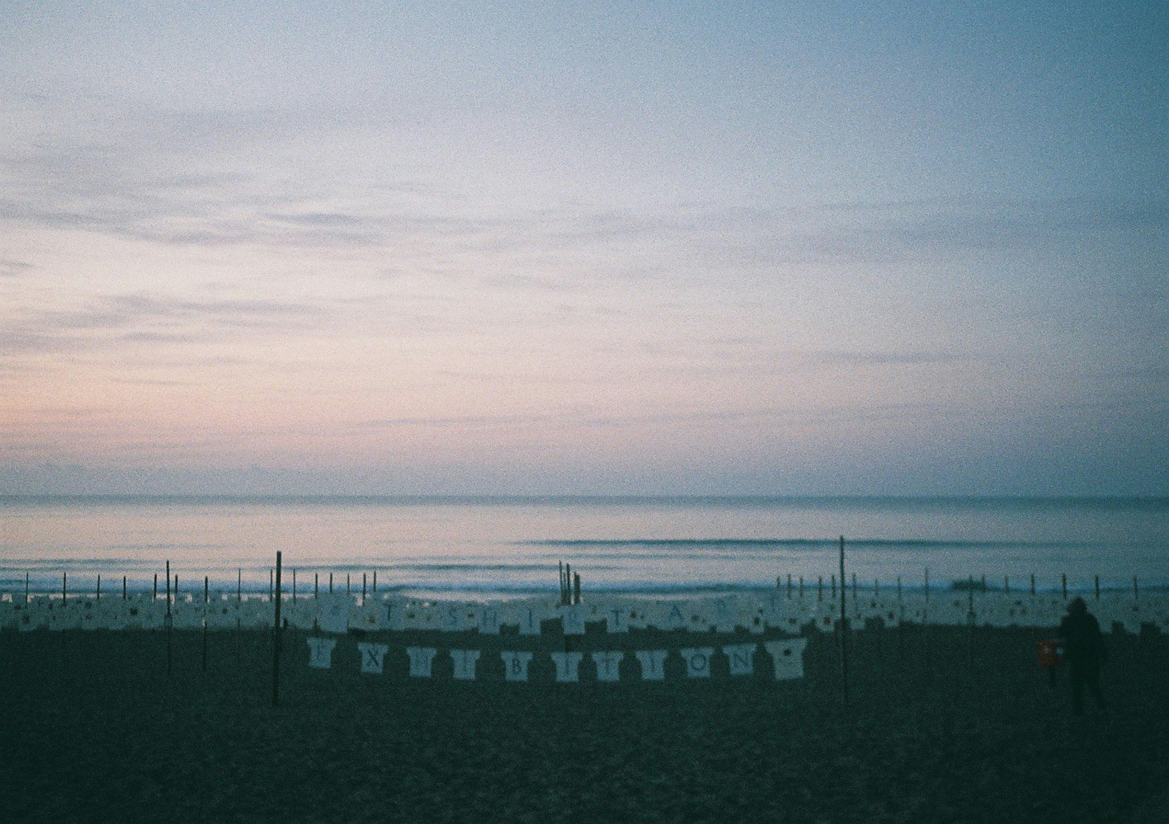 White t-shirts hanging on a beach with a sunset sky