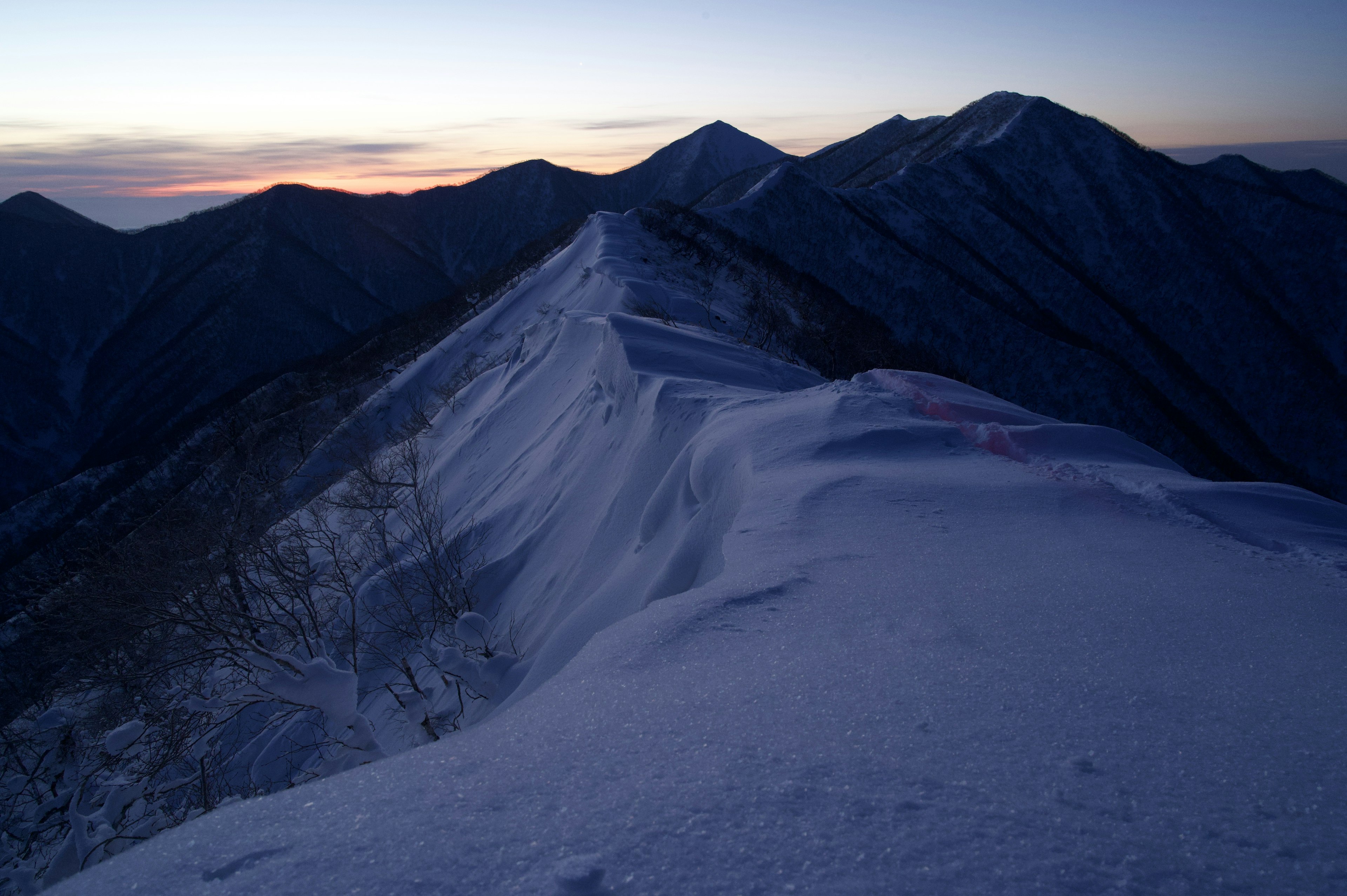 雪に覆われた山の稜線と夕焼けの空