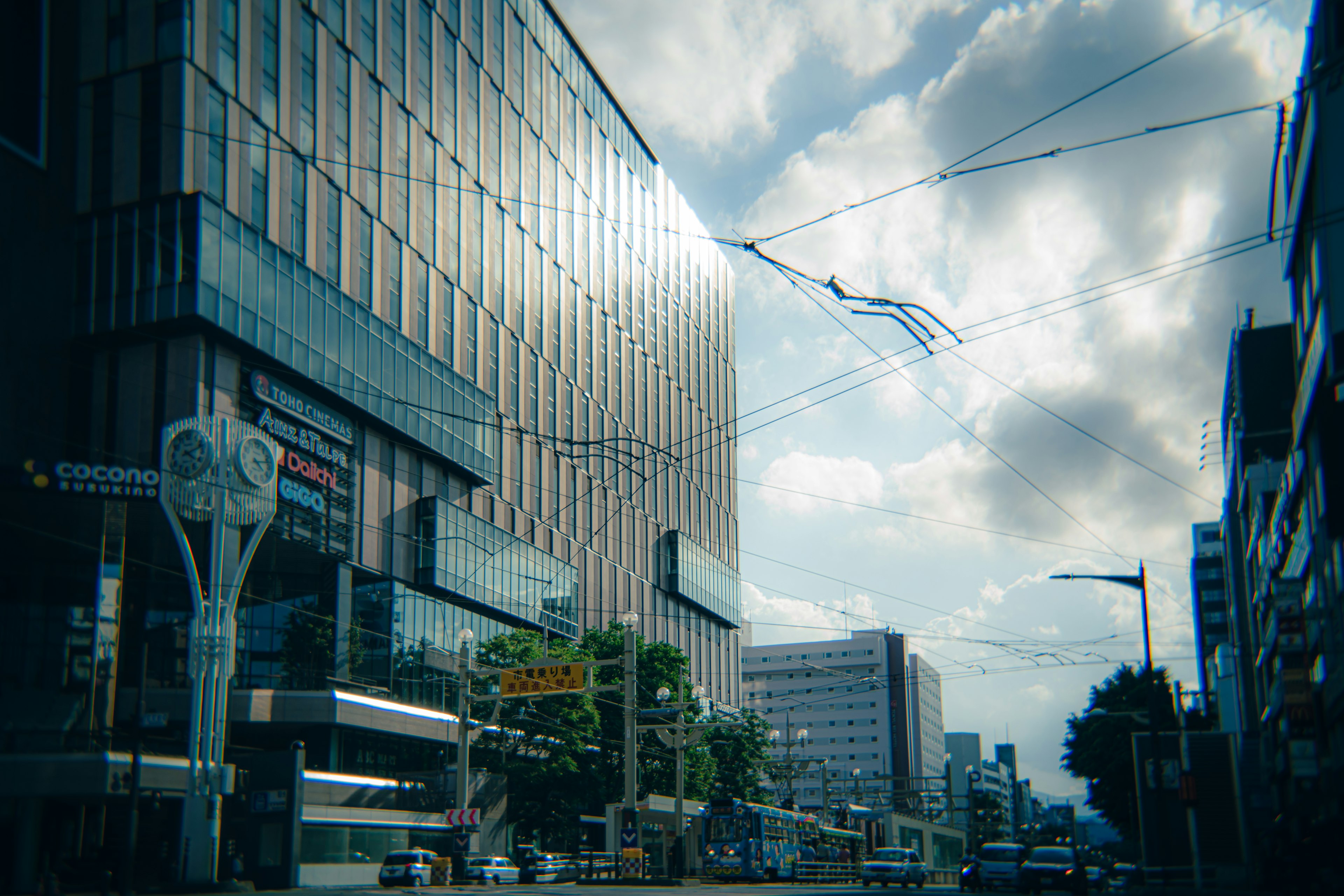 Bangunan modern dengan kaca reflektif dan awan di langit biru