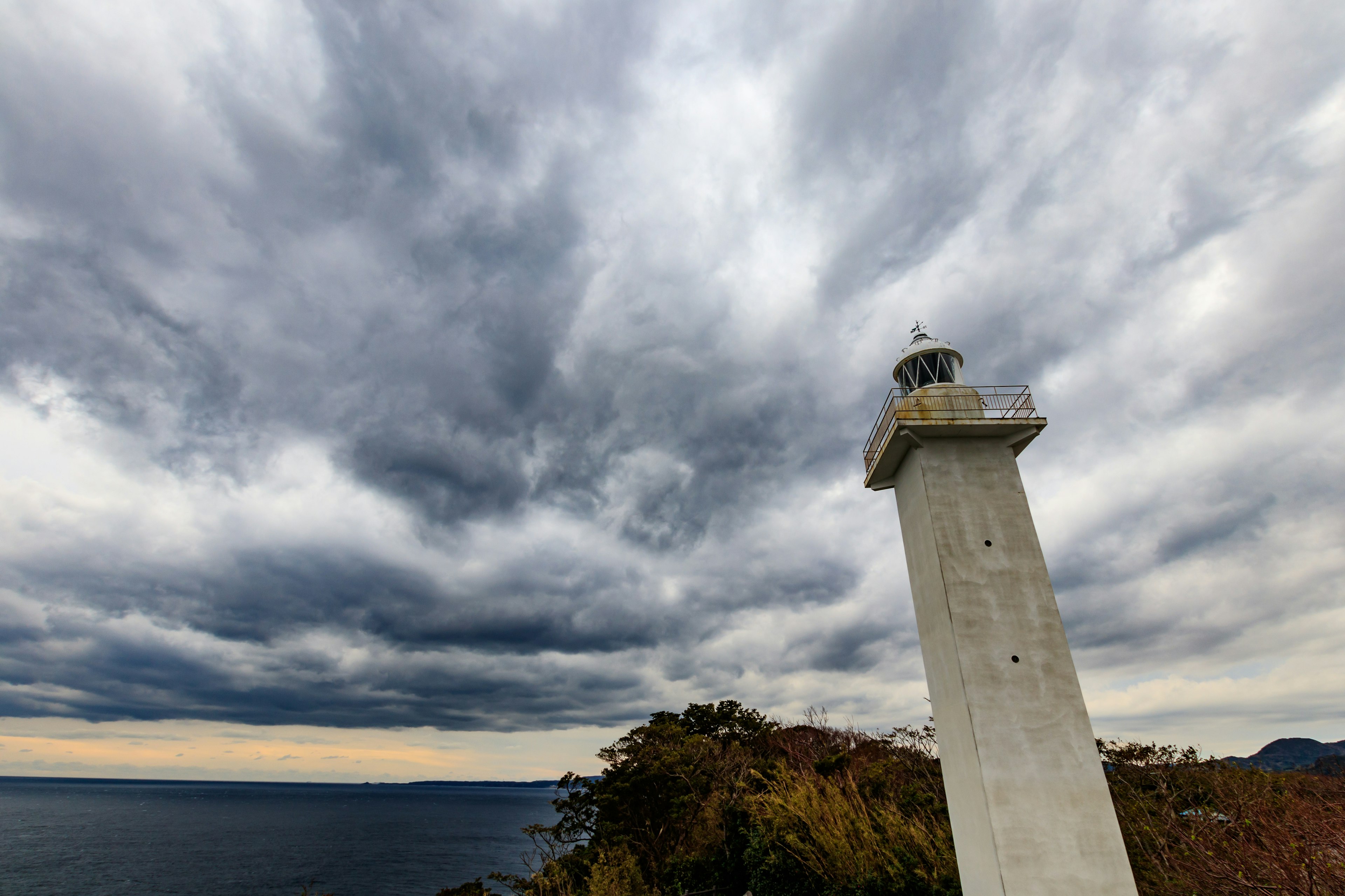 Faro che sovrasta il mare sotto un cielo nuvoloso drammatico