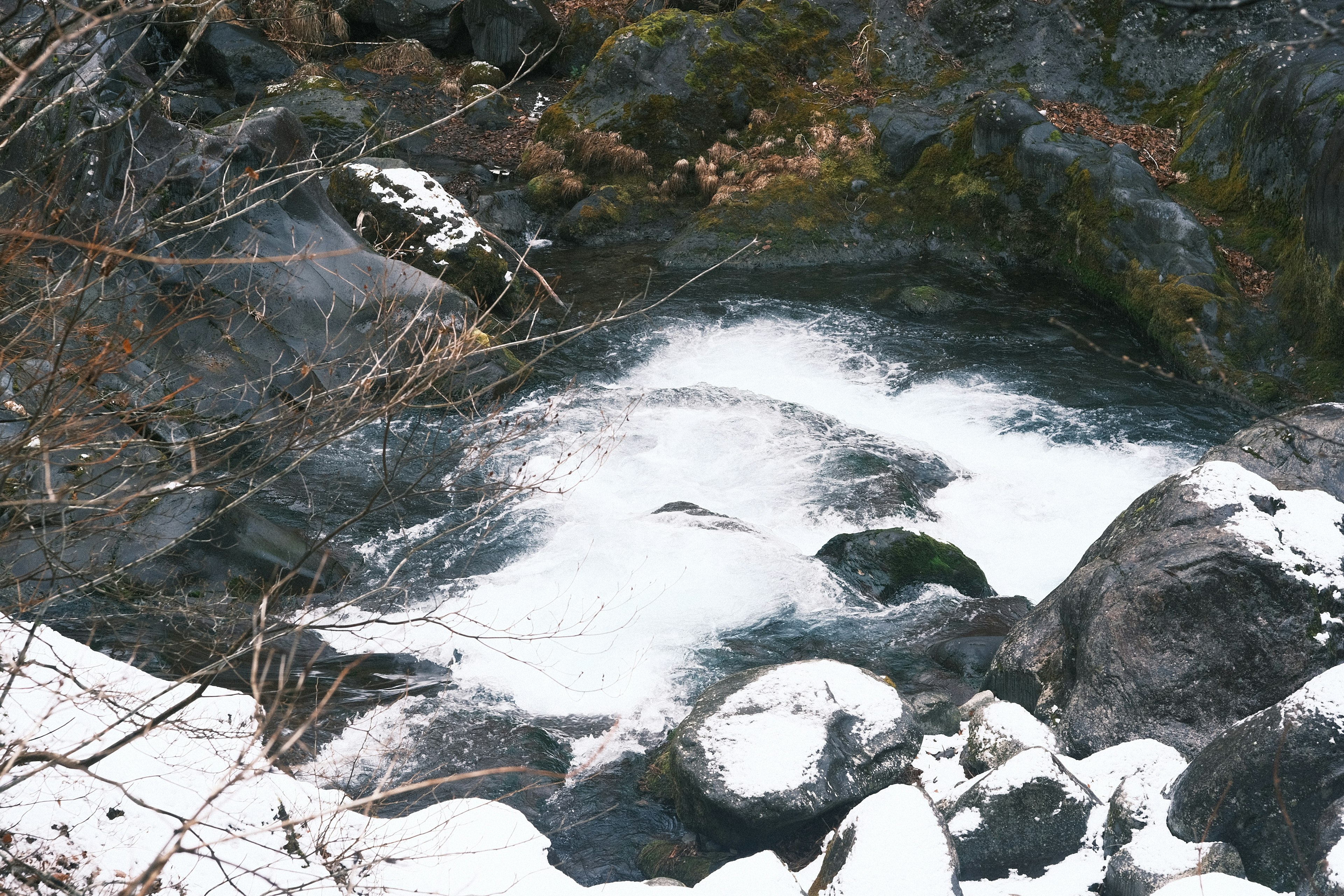 Foto von fließendem Wasser über schneebedeckten Steinen