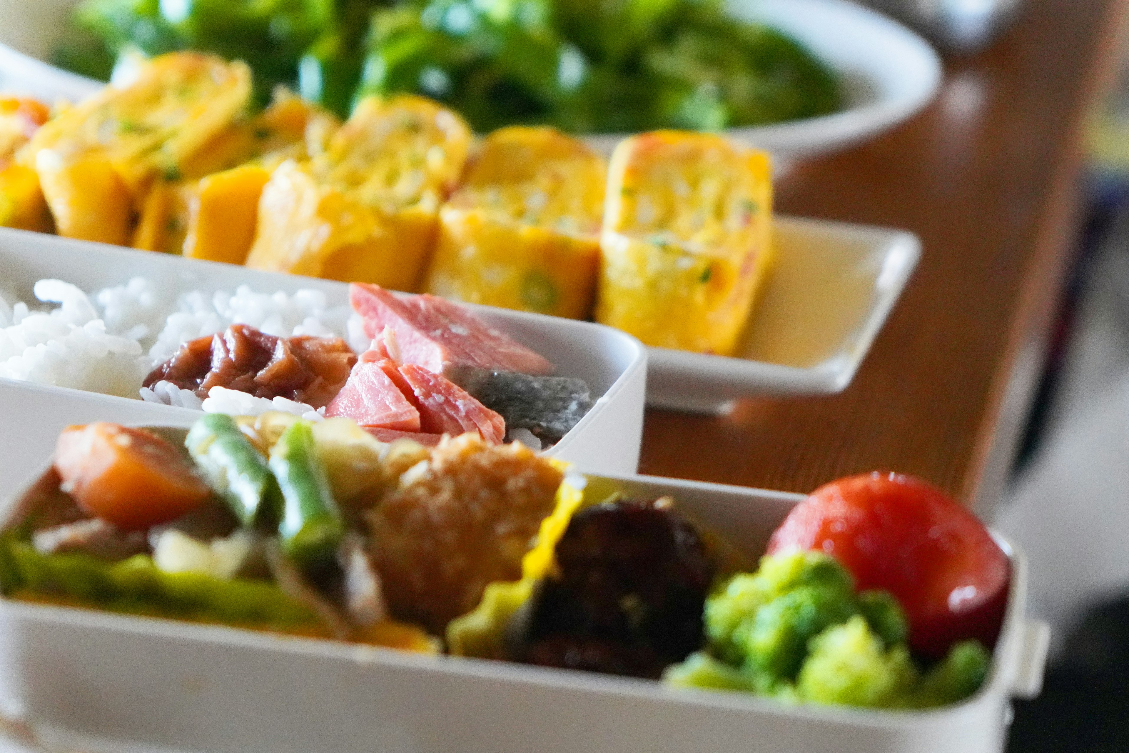 A colorful bento box filled with various dishes including rice vegetables and egg