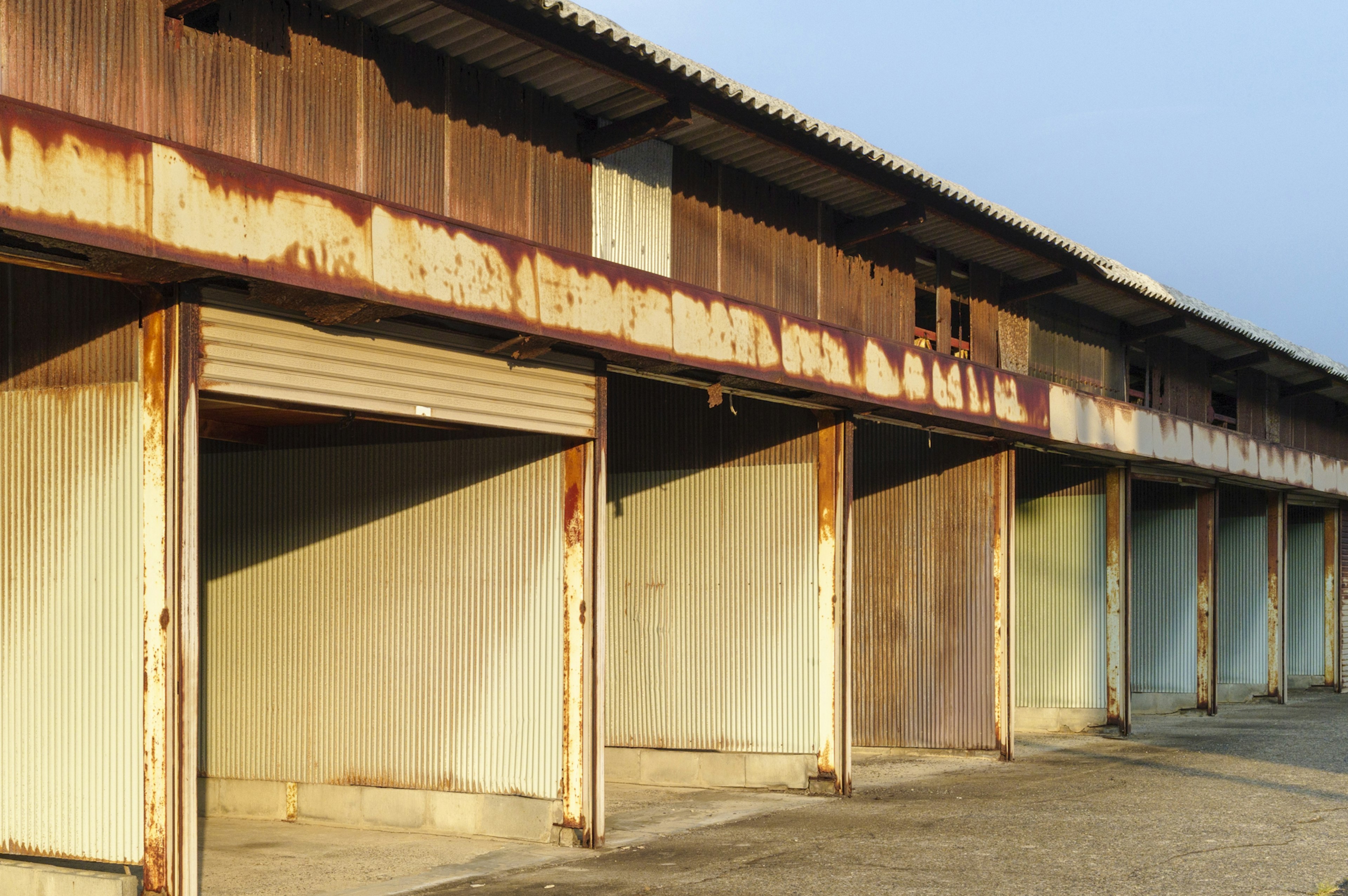 Exterior of an old warehouse with rusty metal walls and a blue sky background