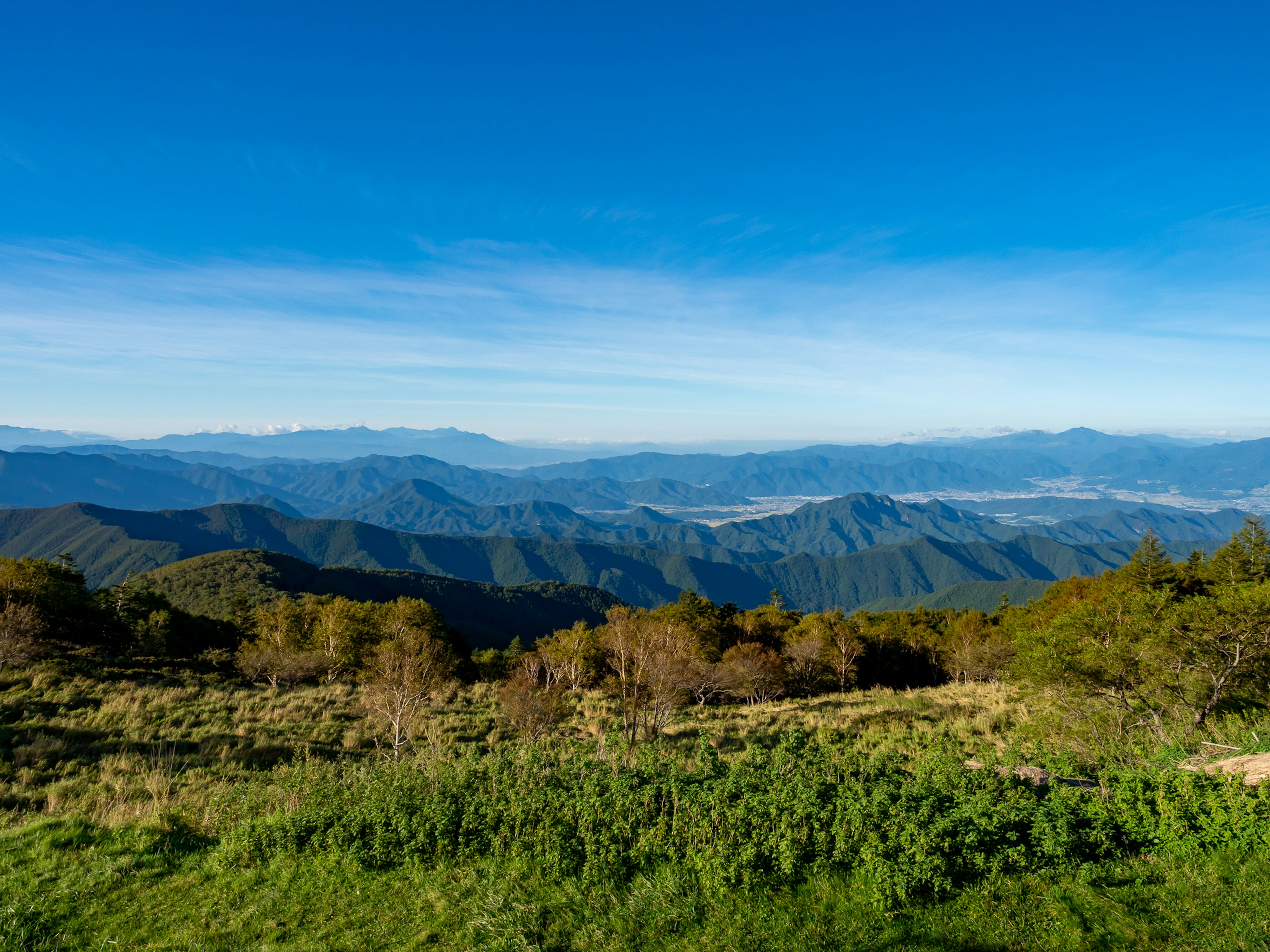 Weite Landschaft von Bergen unter einem blauen Himmel Grüne Wiese und Bäume