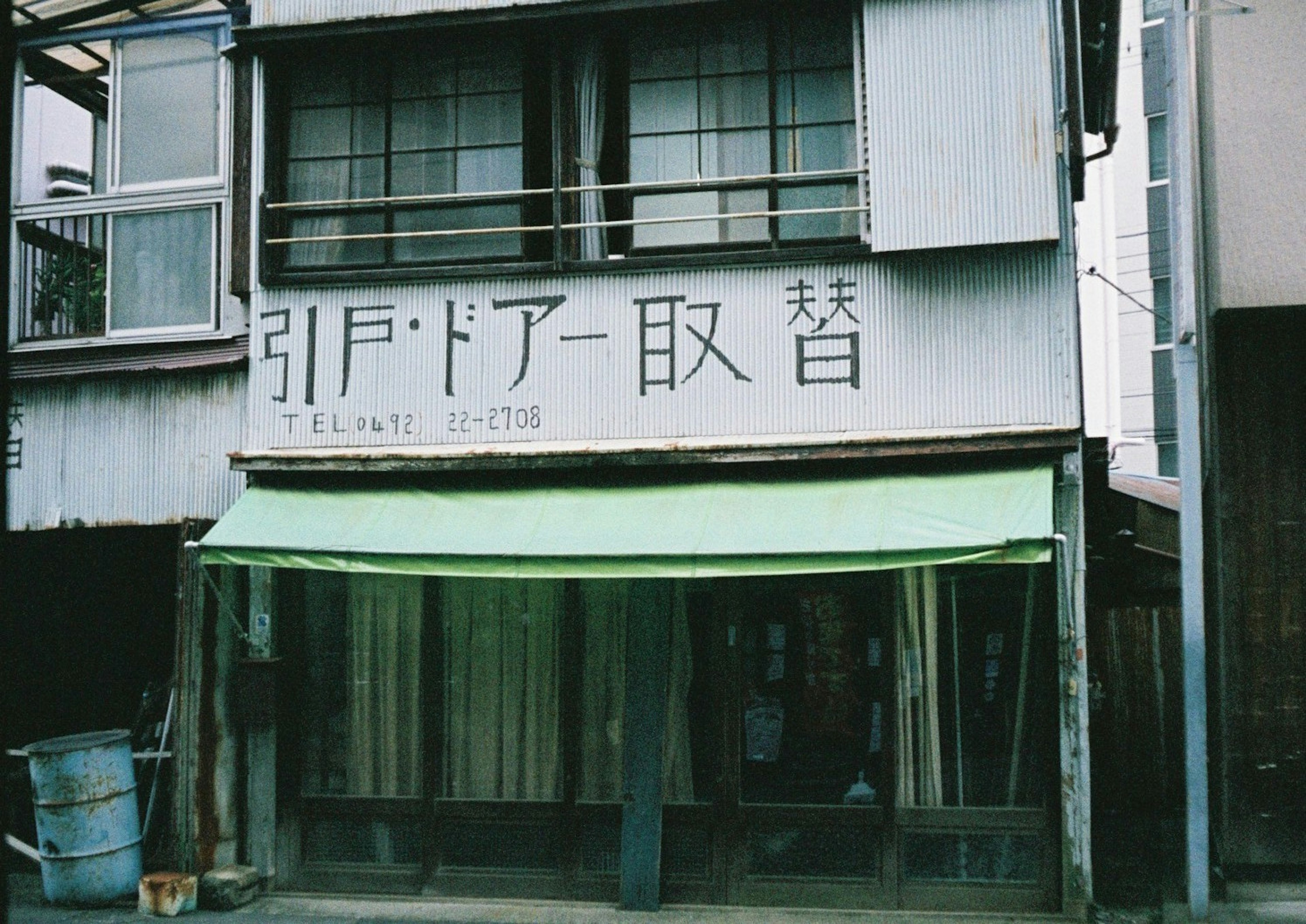 古い建物の外観に緑色のテントがある店の看板