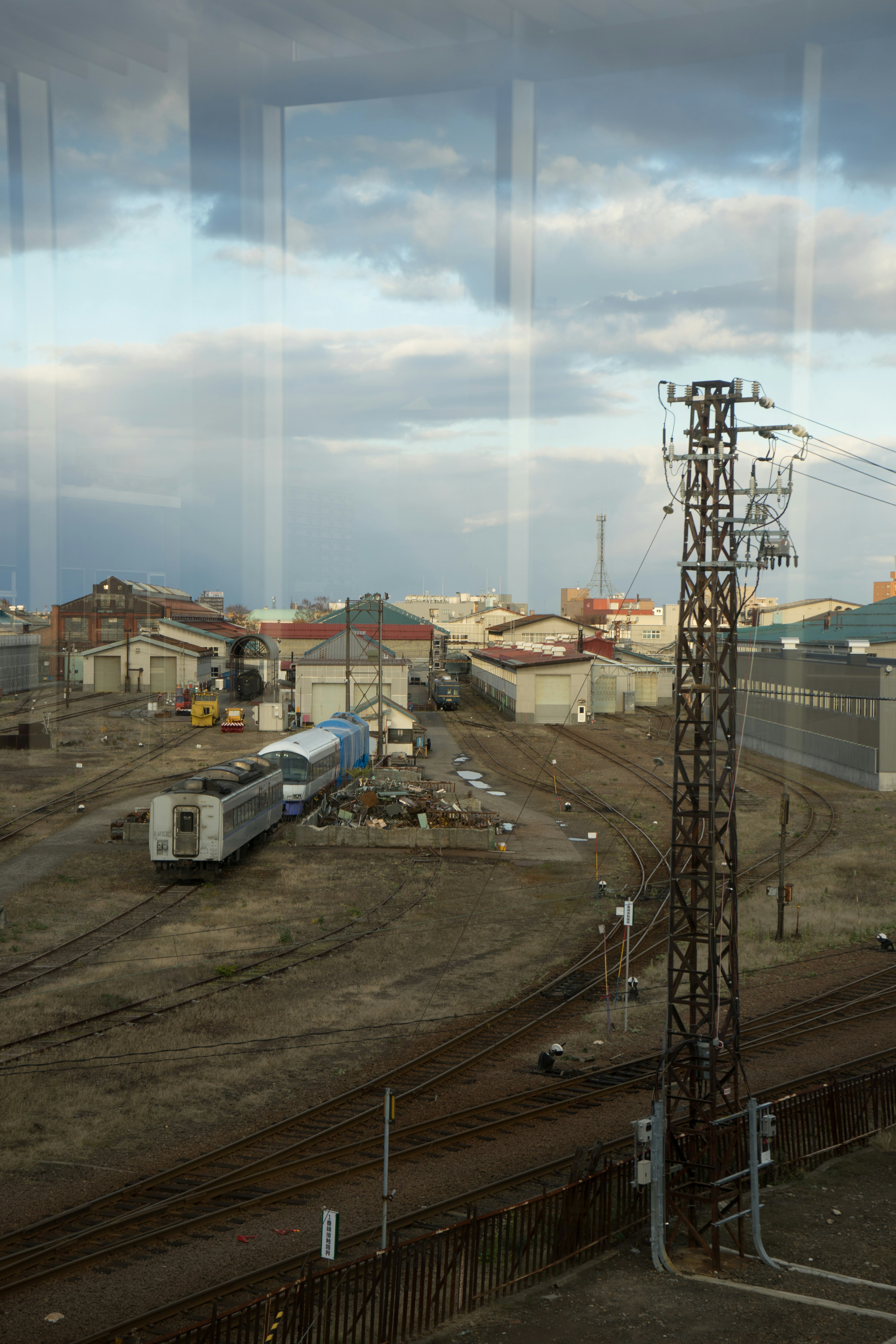 Industrial landscape featuring a power tower and freight train under a cloudy sky