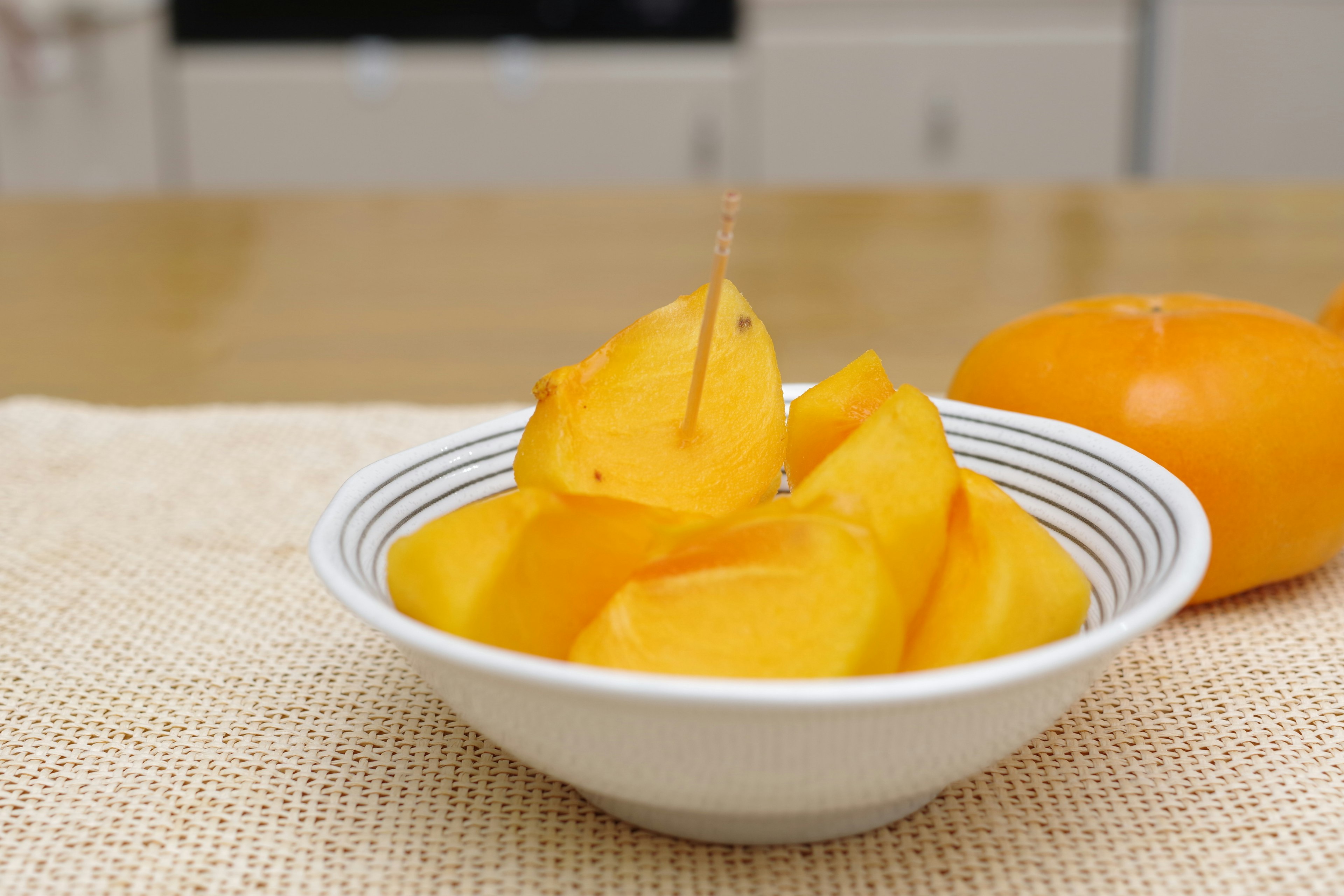 Immagine di fette di frutta arancione disposte in una ciotola bianca