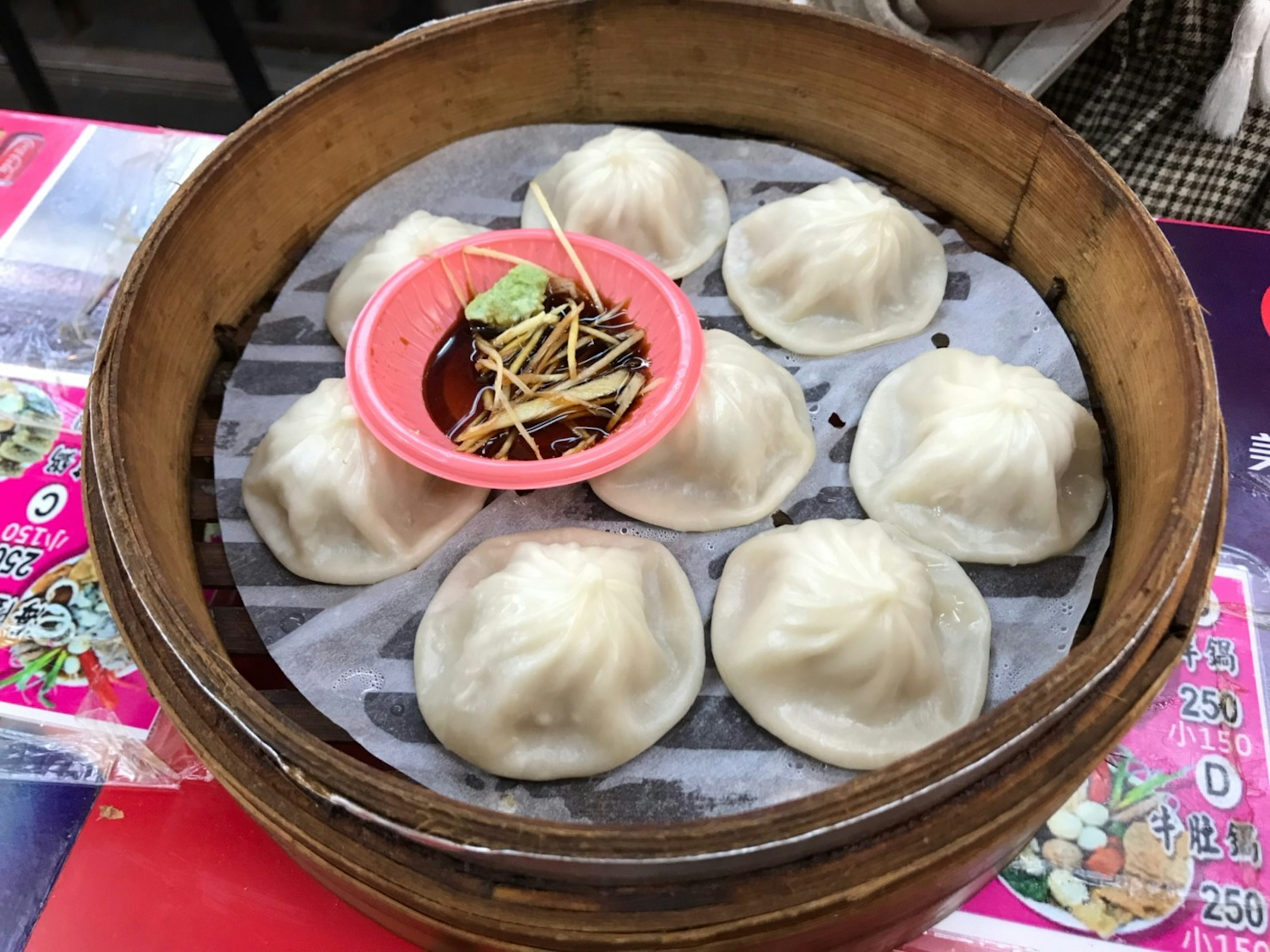 Steamed dumplings in a bamboo steamer with dipping sauce