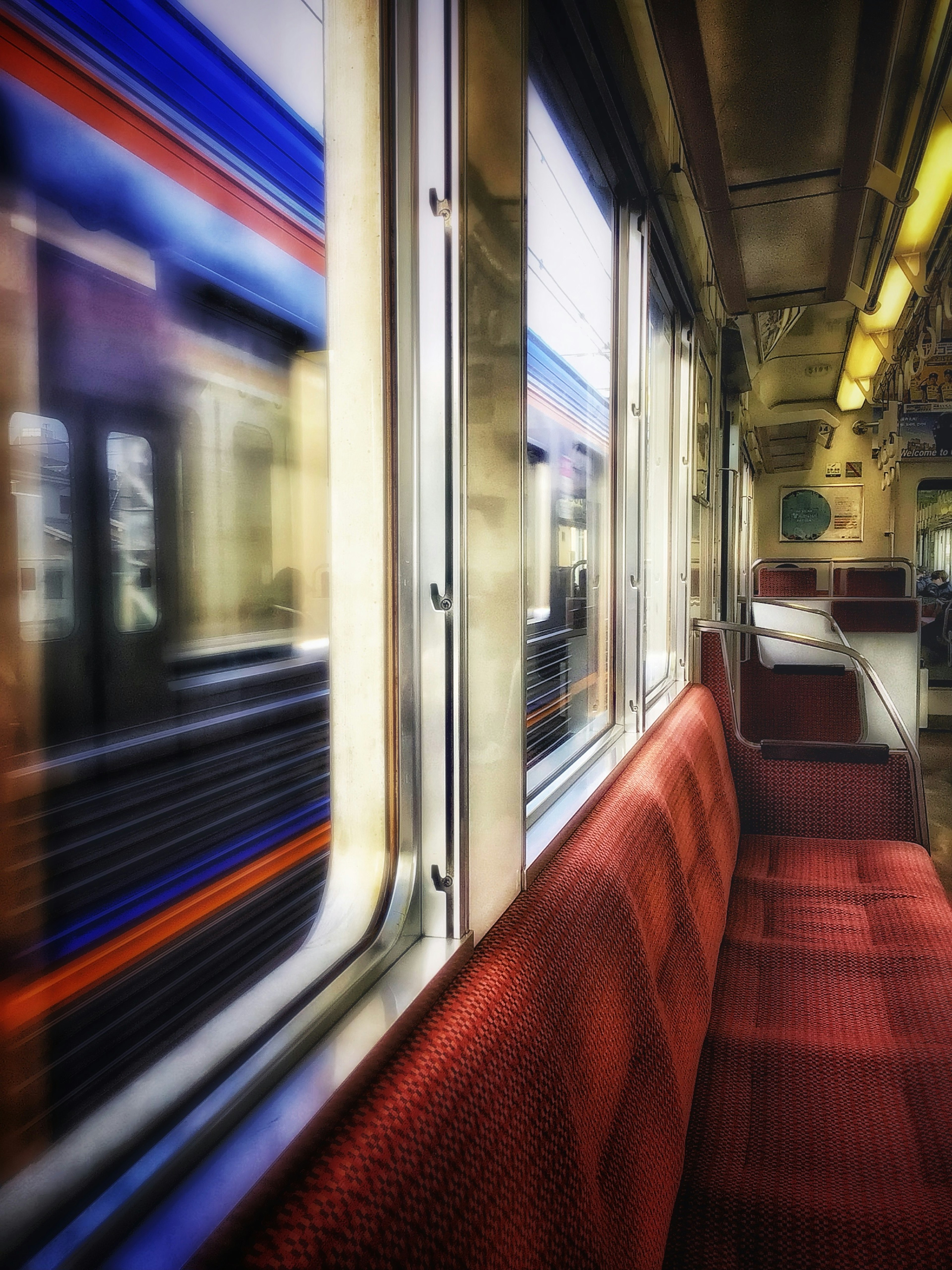 Interior of a subway train with red seats and a blurred view through the window