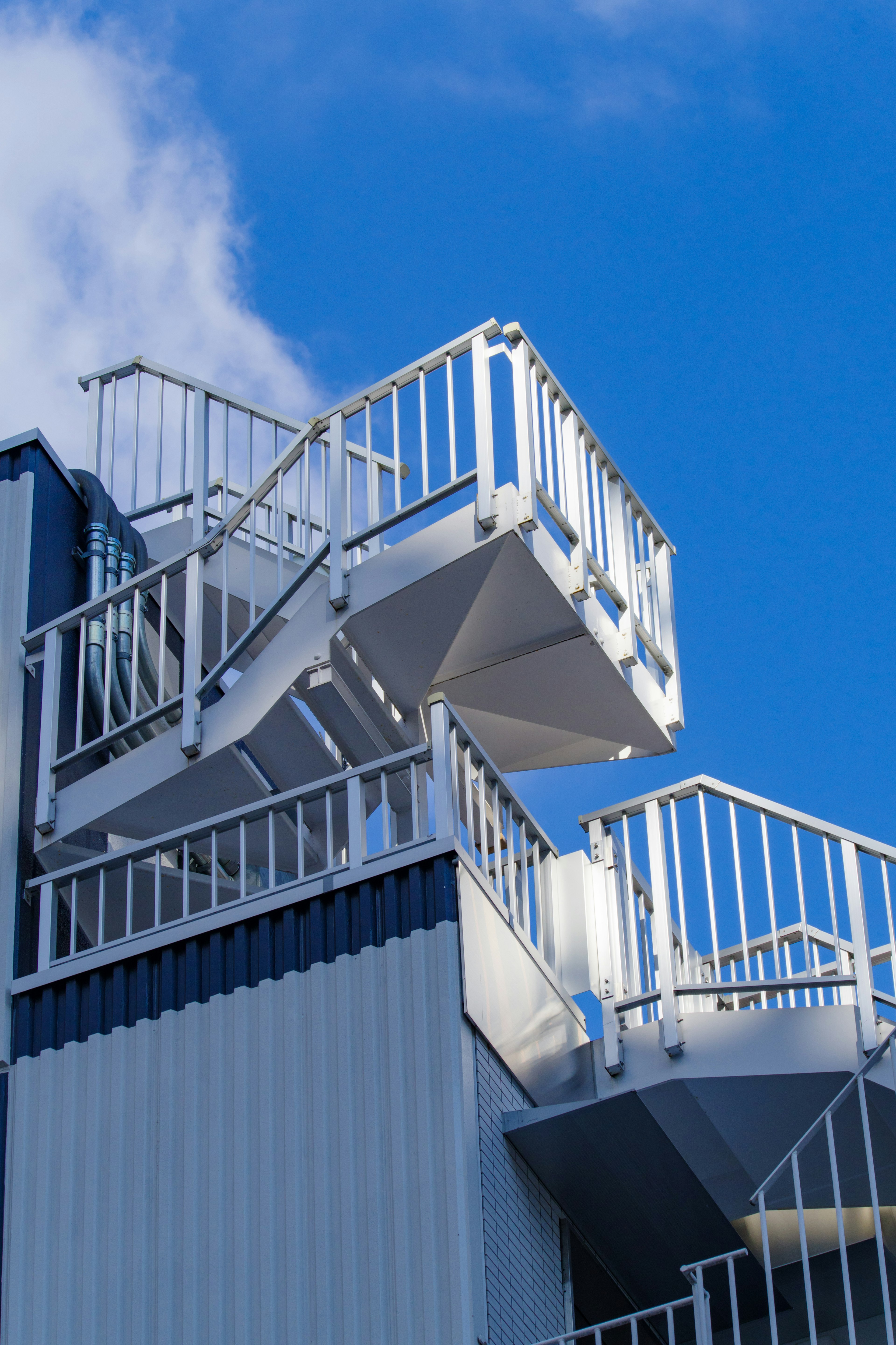 Modern staircase with white railings against a blue sky