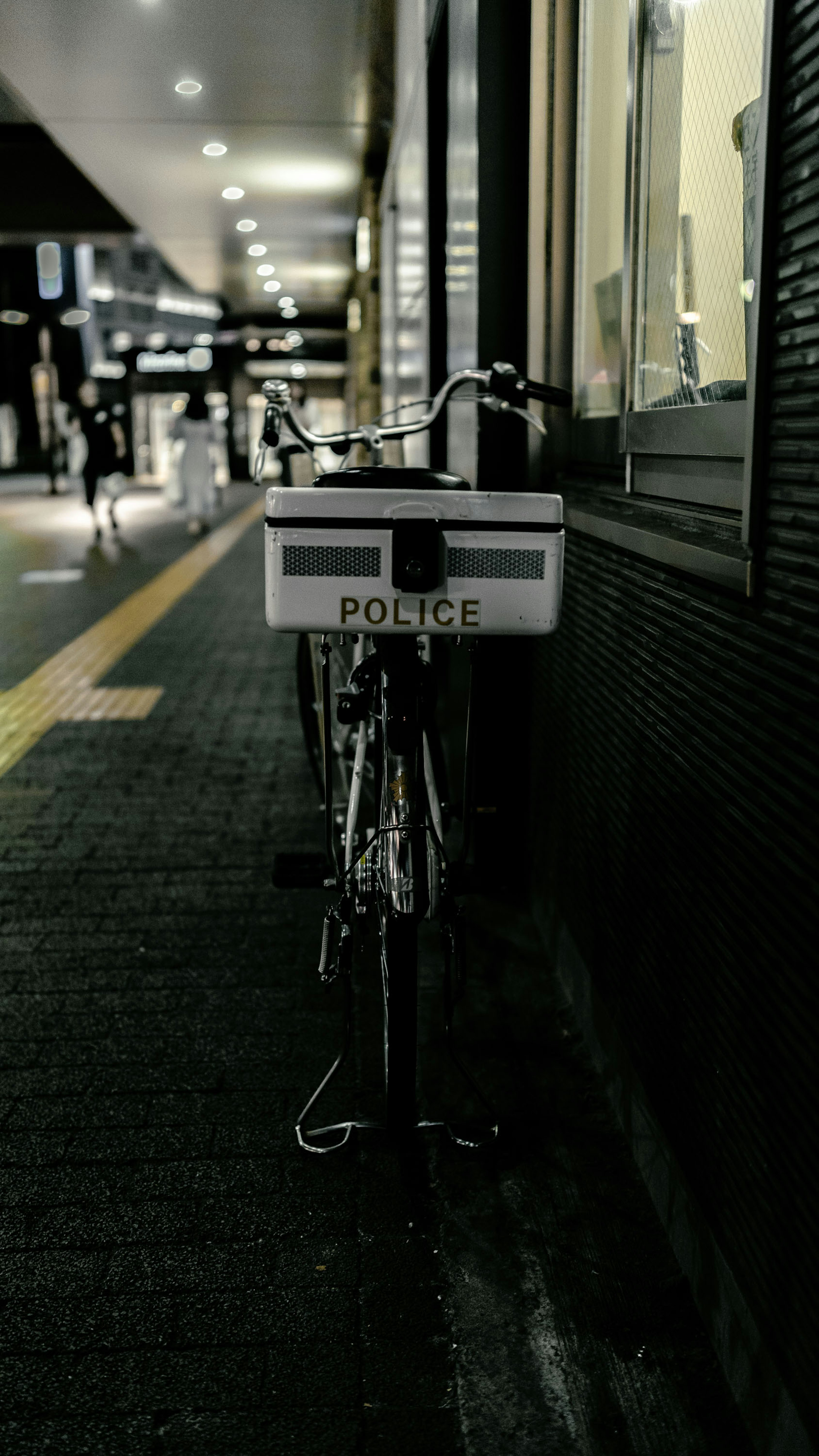 Una bicicleta de policía estacionada en una acera por la noche