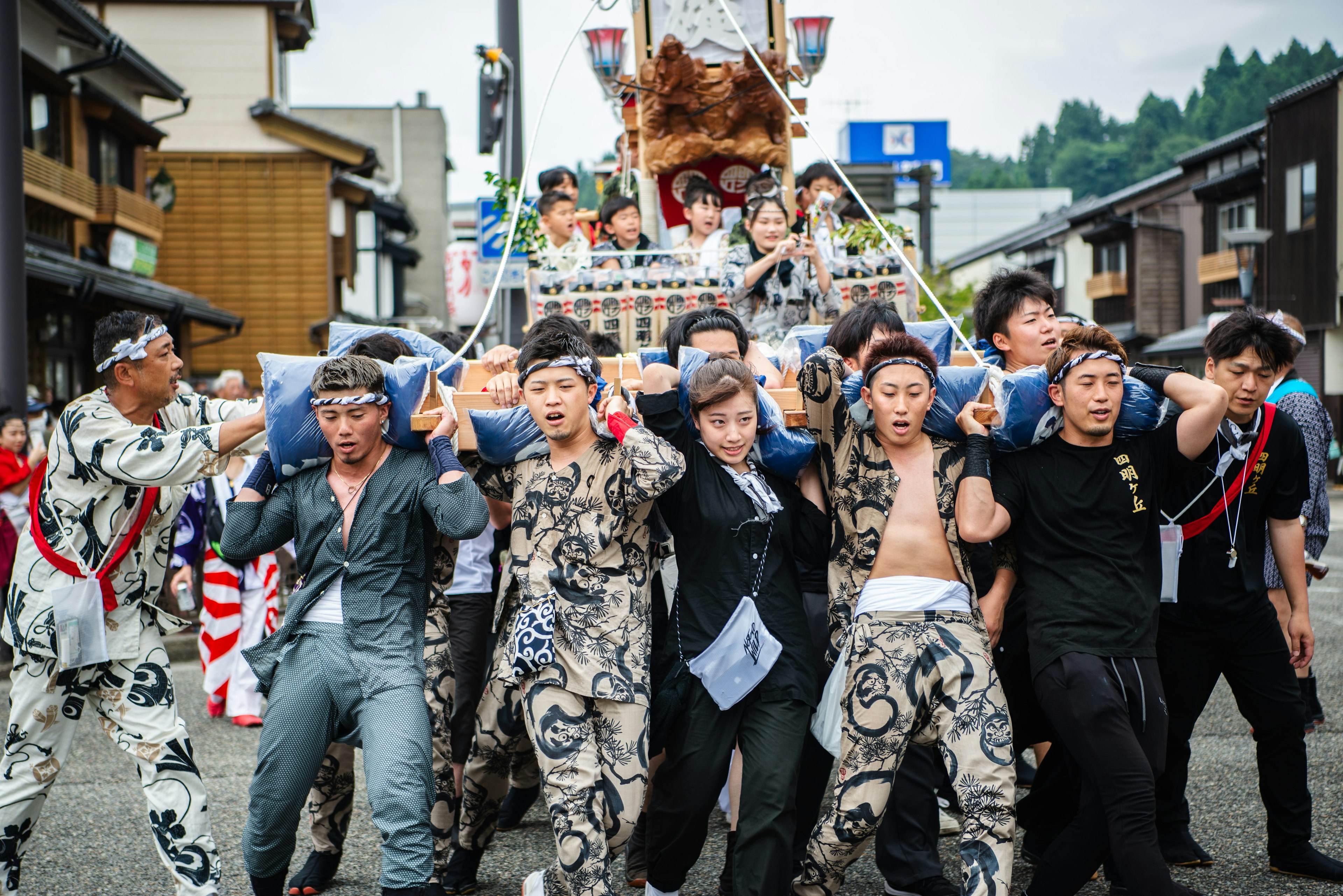 祭りの行列で神輿を担ぐ男性たちが伝統的な衣装を着ている