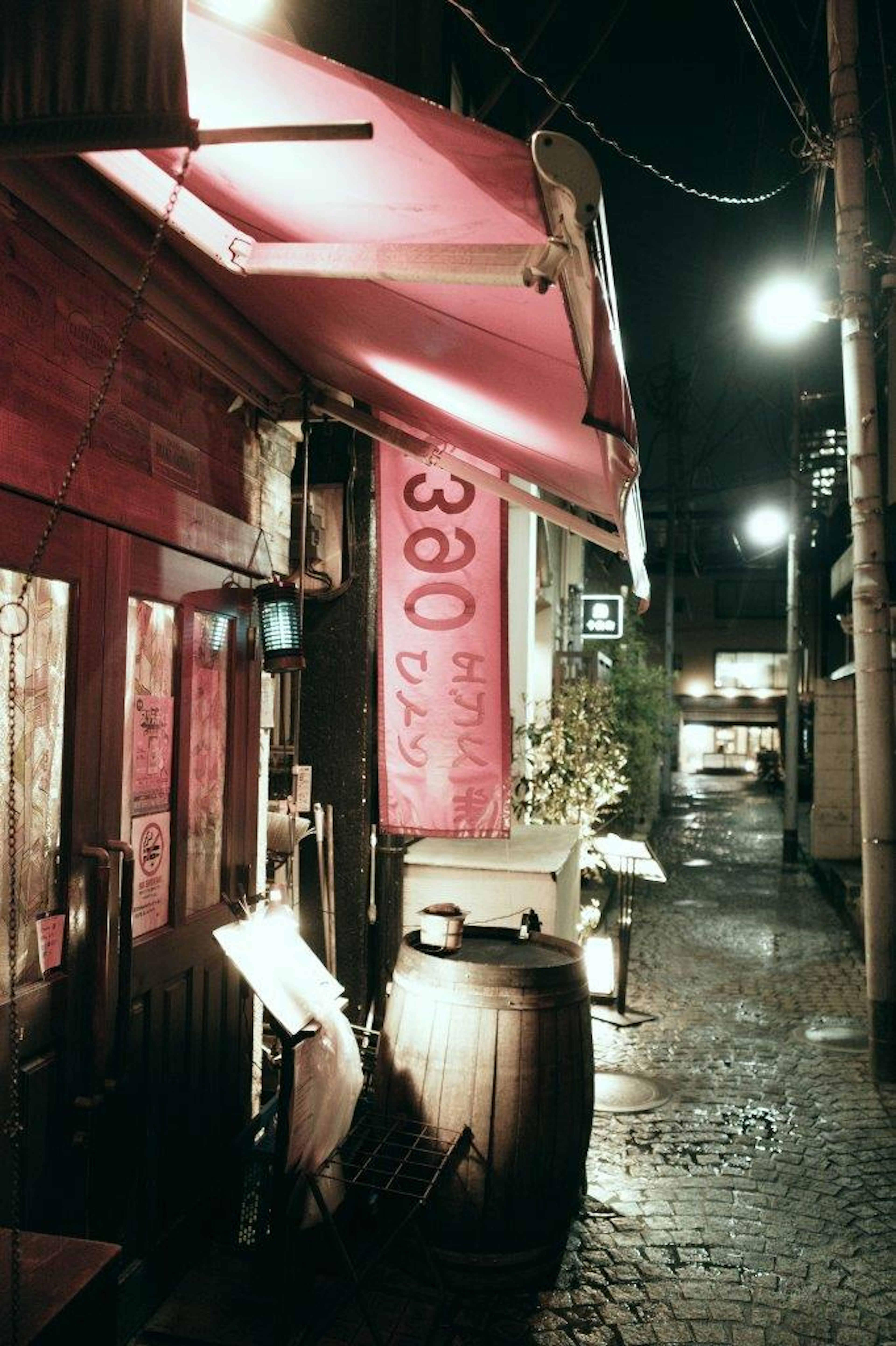 Ein rotes Schild Izakaya in einer Kopfsteinpflastergasse bei Nacht